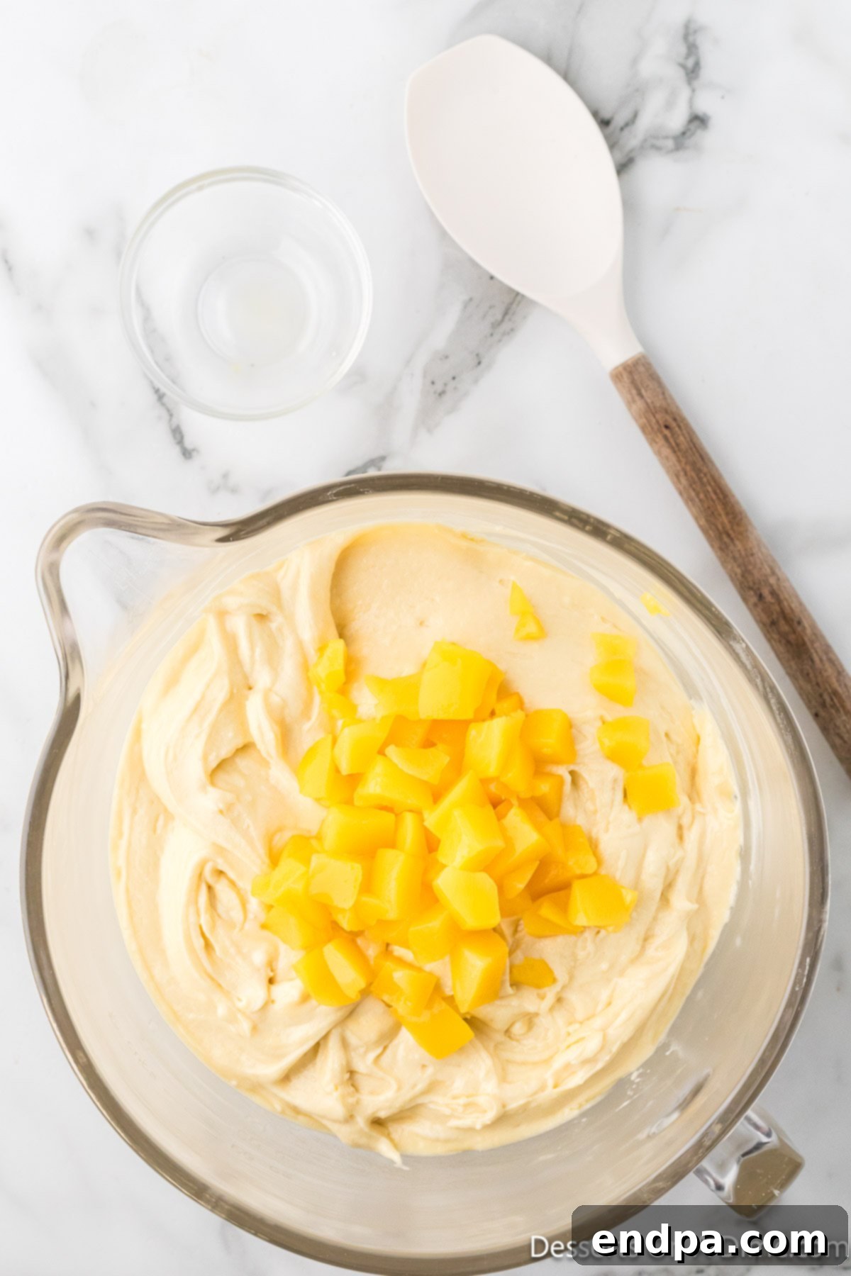 Diced peaches being gently folded into the rich cake batter, ready for baking.