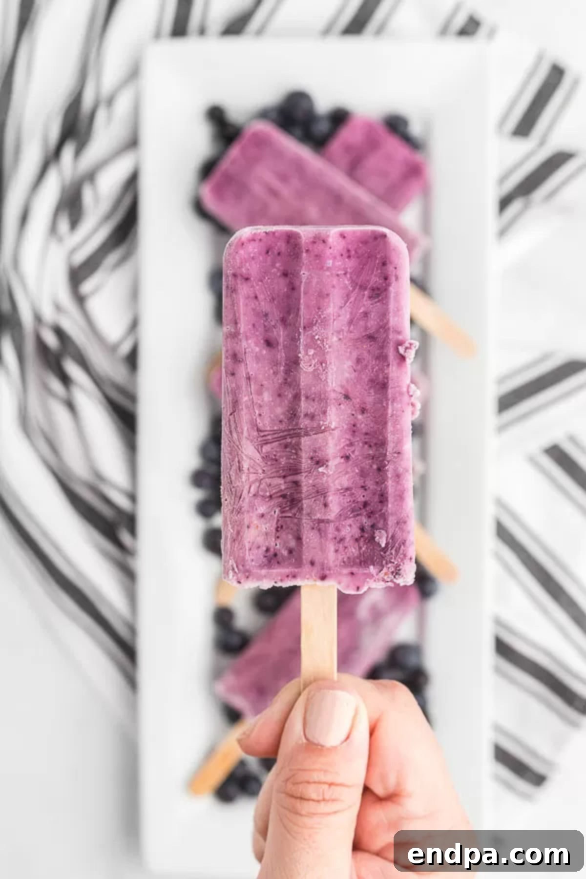 Refreshing Blueberry Yogurt Pops 7 Close up photo of several blueberry yogurt popsicles, showing their creamy texture and vibrant color.