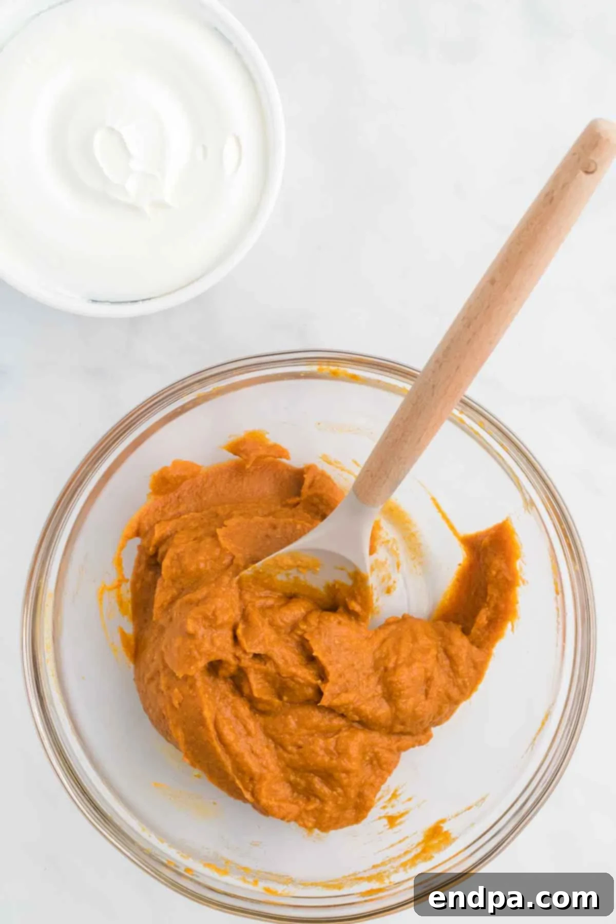 Pumpkin puree in a mixing bowl combined with instant pudding mix and milk, ready for mixing.