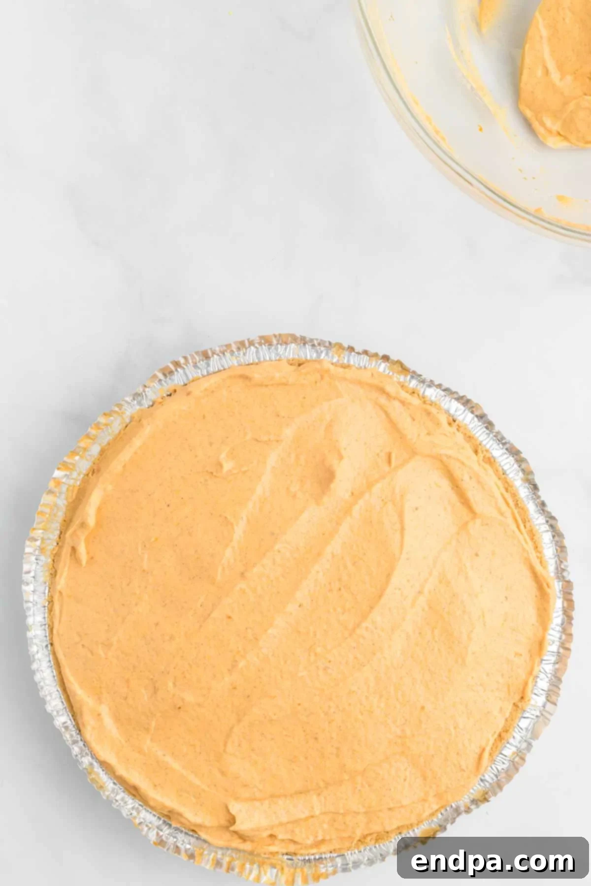 The smooth pumpkin mixture is spread evenly into the graham cracker pie crust.