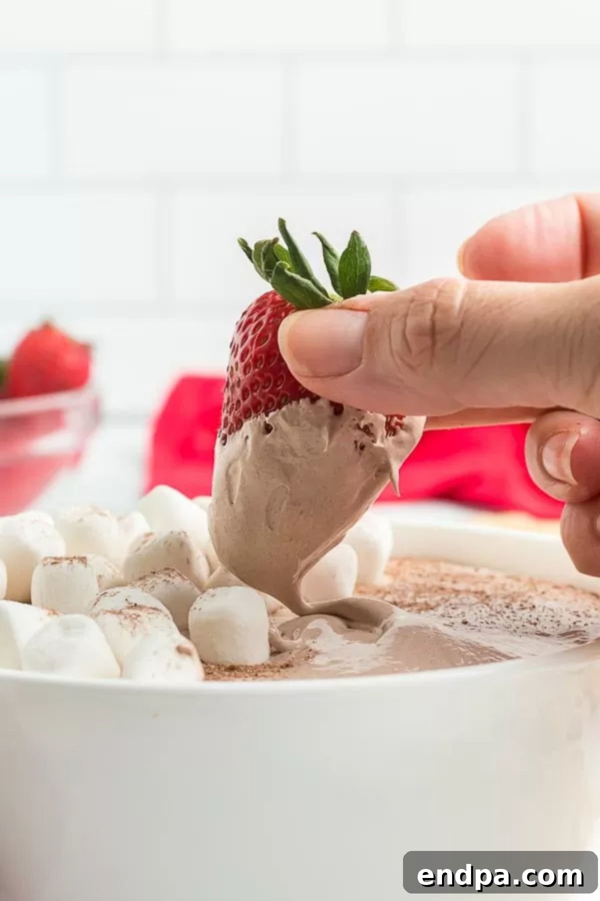 Decadent Hot Chocolate Dip 7 A vibrant red strawberry being dipped into a bowl of creamy Hot Chocolate Dessert Dip, showcasing its delightful texture and inviting appeal.