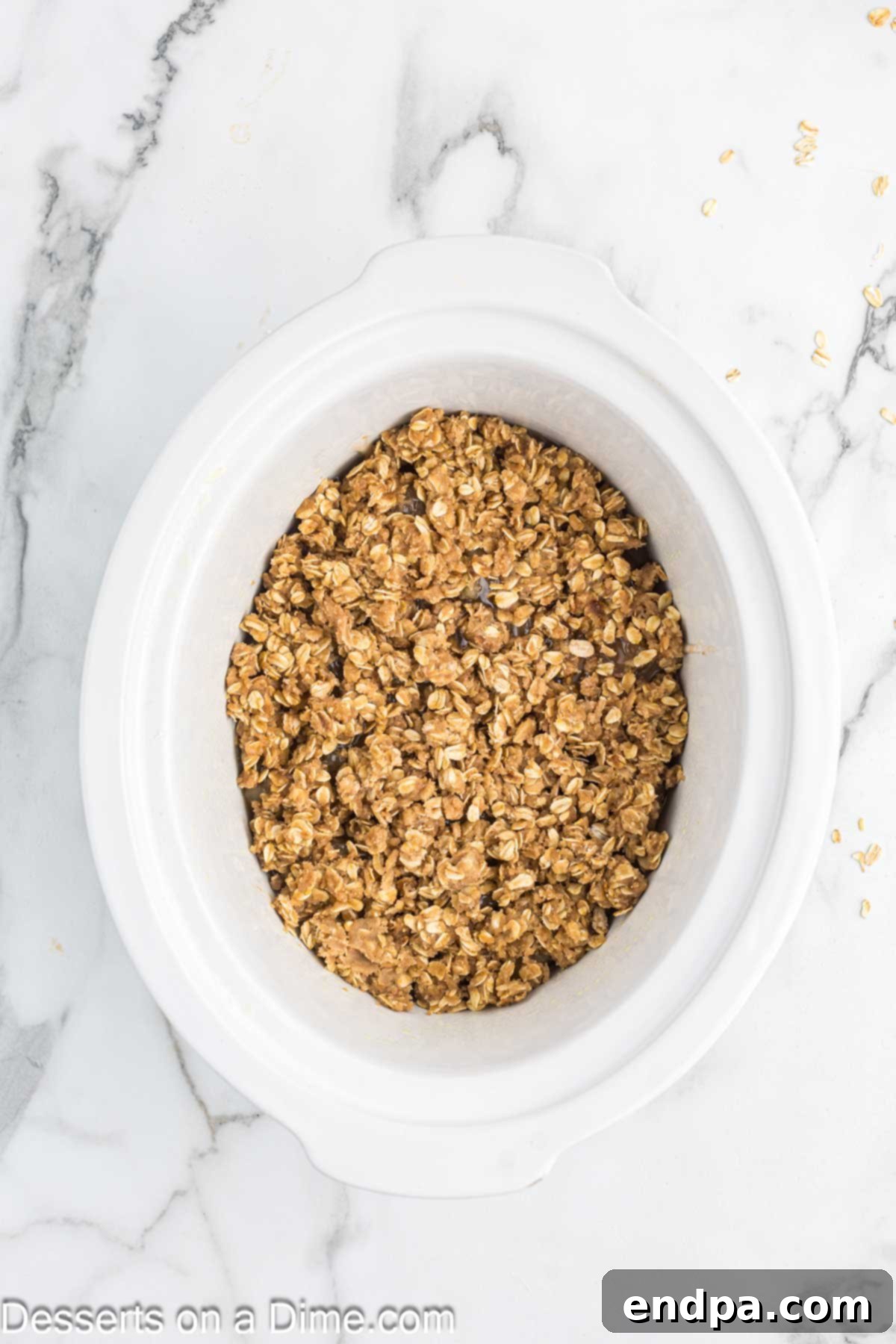 Cozy Slow Cooker Apple Crisp 6 Topping spread on pie filling.