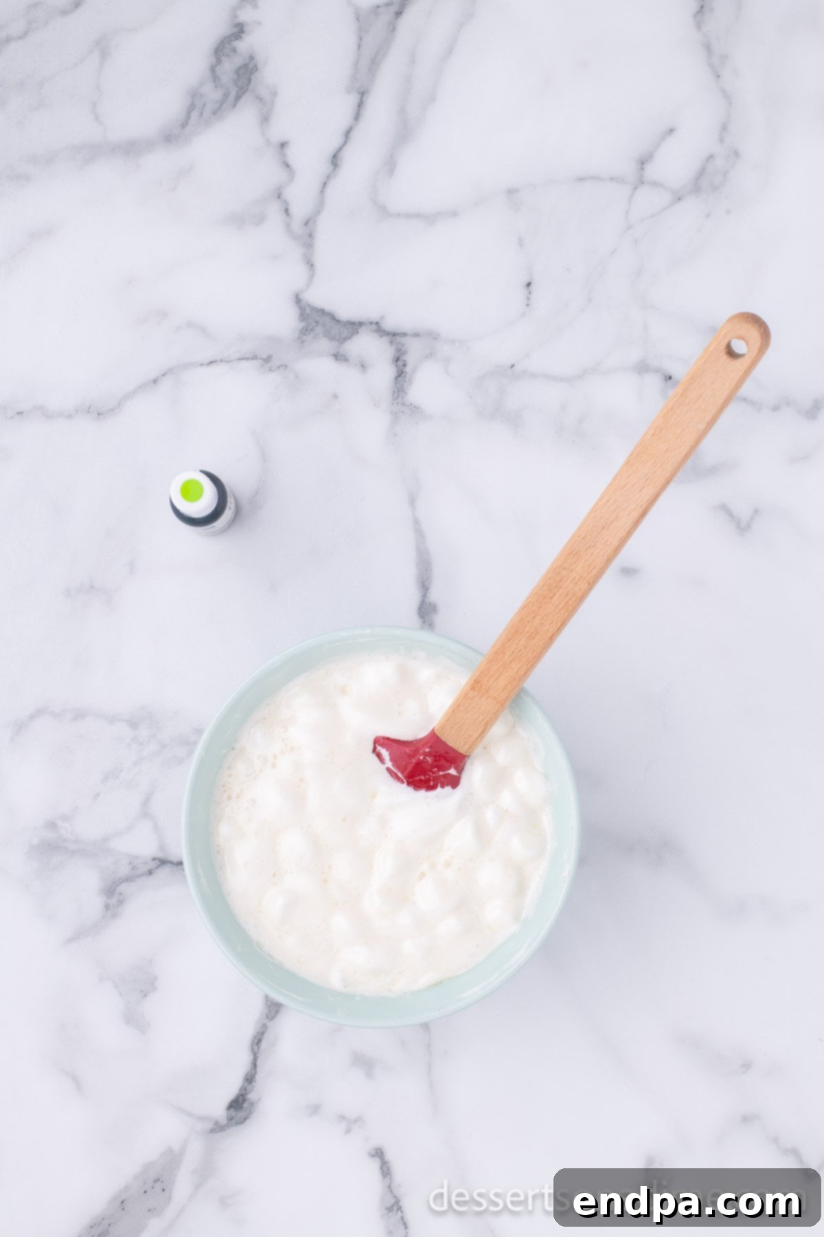 Festive Grinch Popcorn Mix 4 Melted butter and mini marshmallows combined into a smooth, gooey mixture in a microwave-safe bowl.