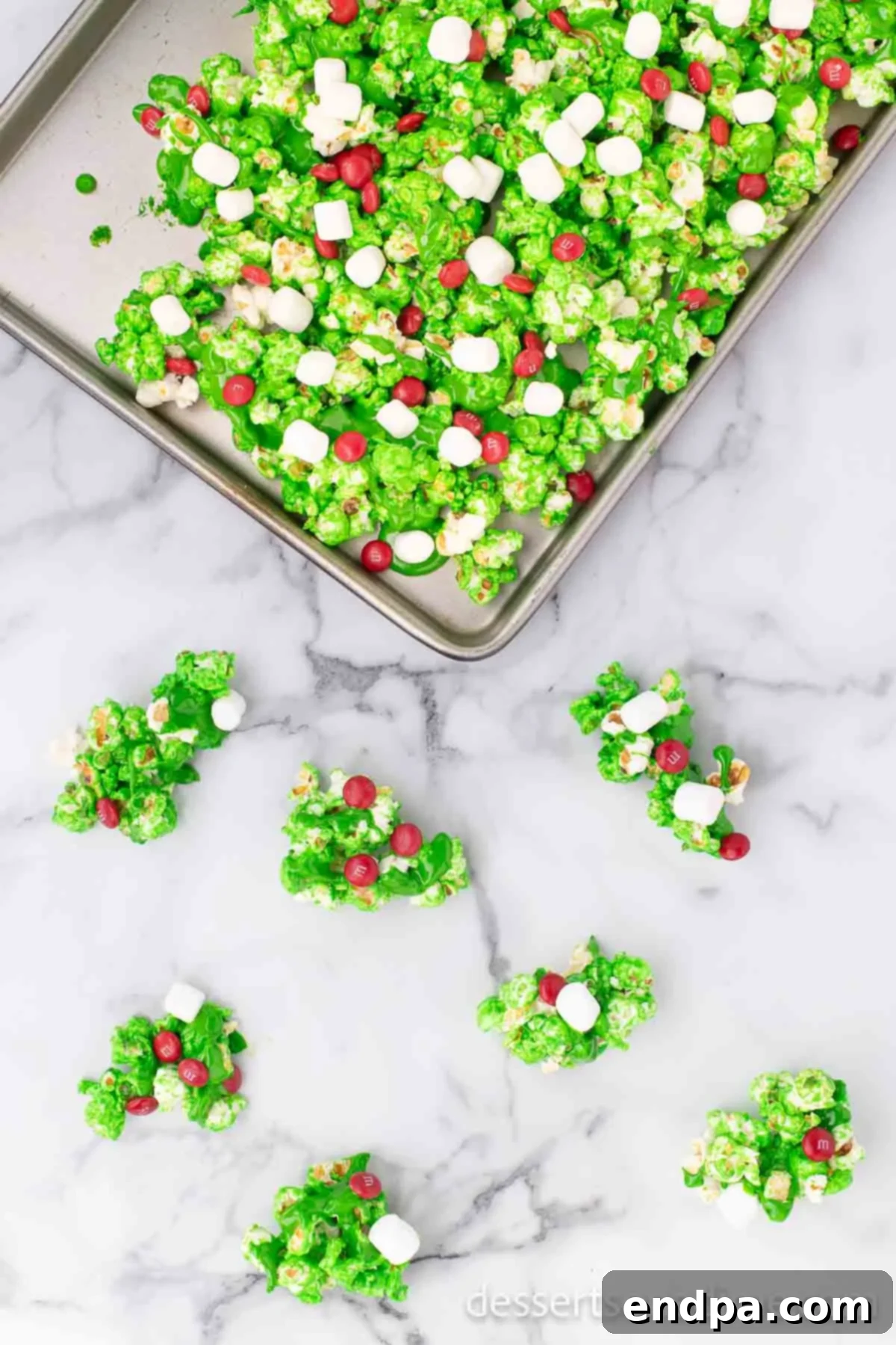 Festive Grinch Popcorn Mix 8 Remaining mini marshmallows and red M&Ms sprinkled generously on top of the green Grinch Popcorn.
