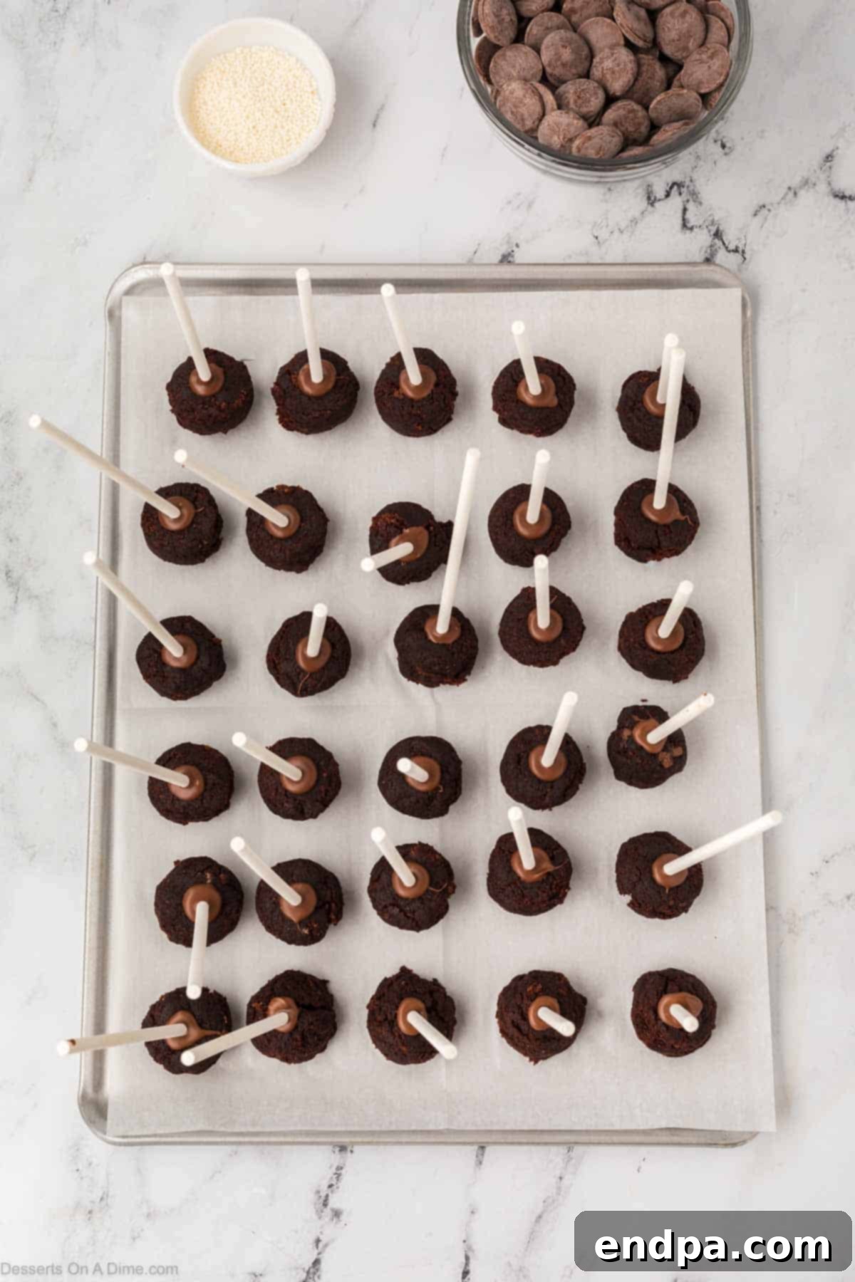 Cake pops with sticks inserted, chilling on a baking sheet.