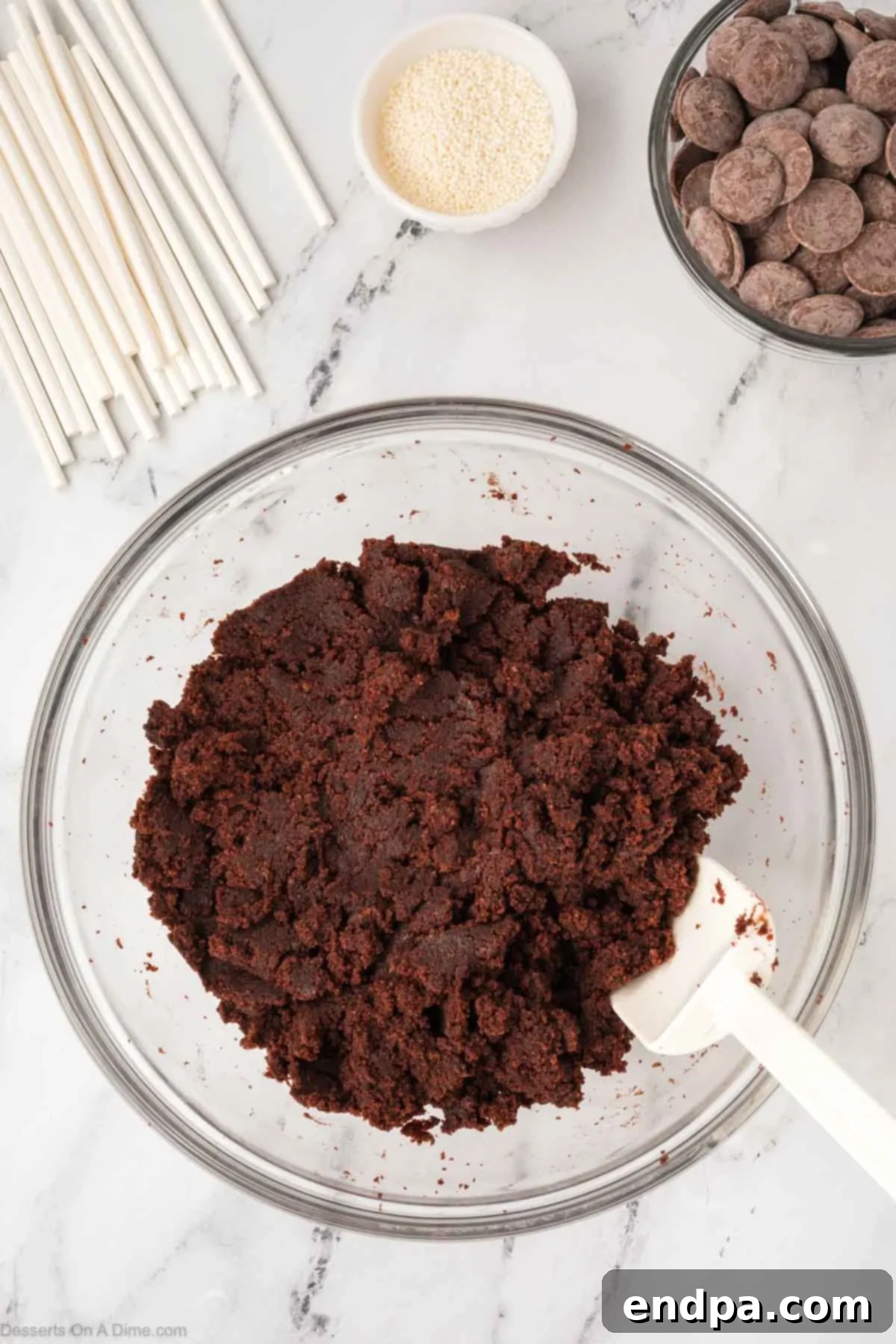 Crumbled cake and chocolate frosting combined in a mixing bowl.