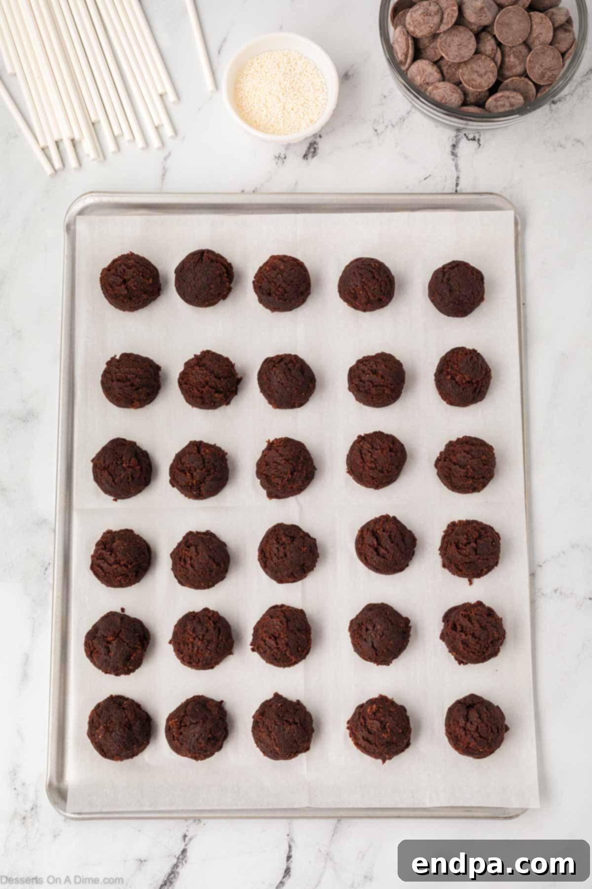 Formed chocolate cake balls arranged on a lined baking sheet.