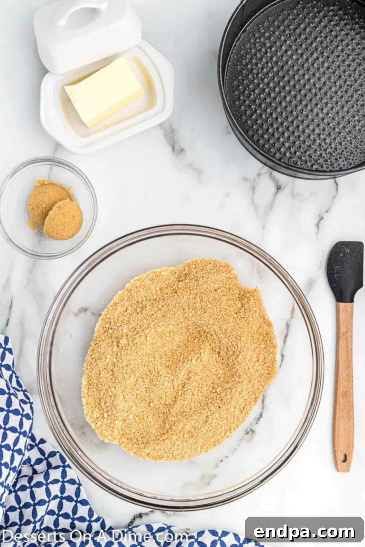 A mixing bowl filled with finely crushed graham crackers, ready for butter and sugar.