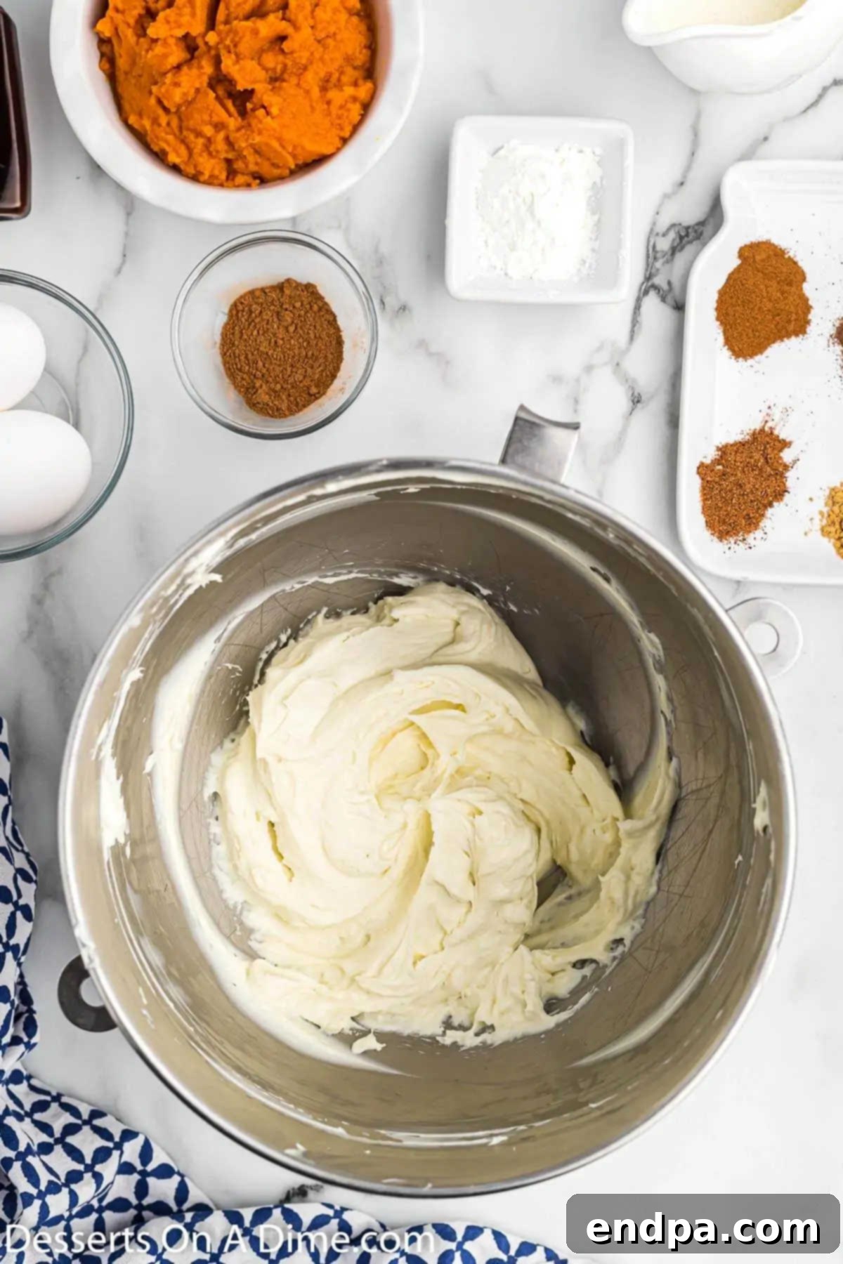 A mixing bowl containing softened cream cheese and granulated sugar, being beaten to a light and fluffy consistency.