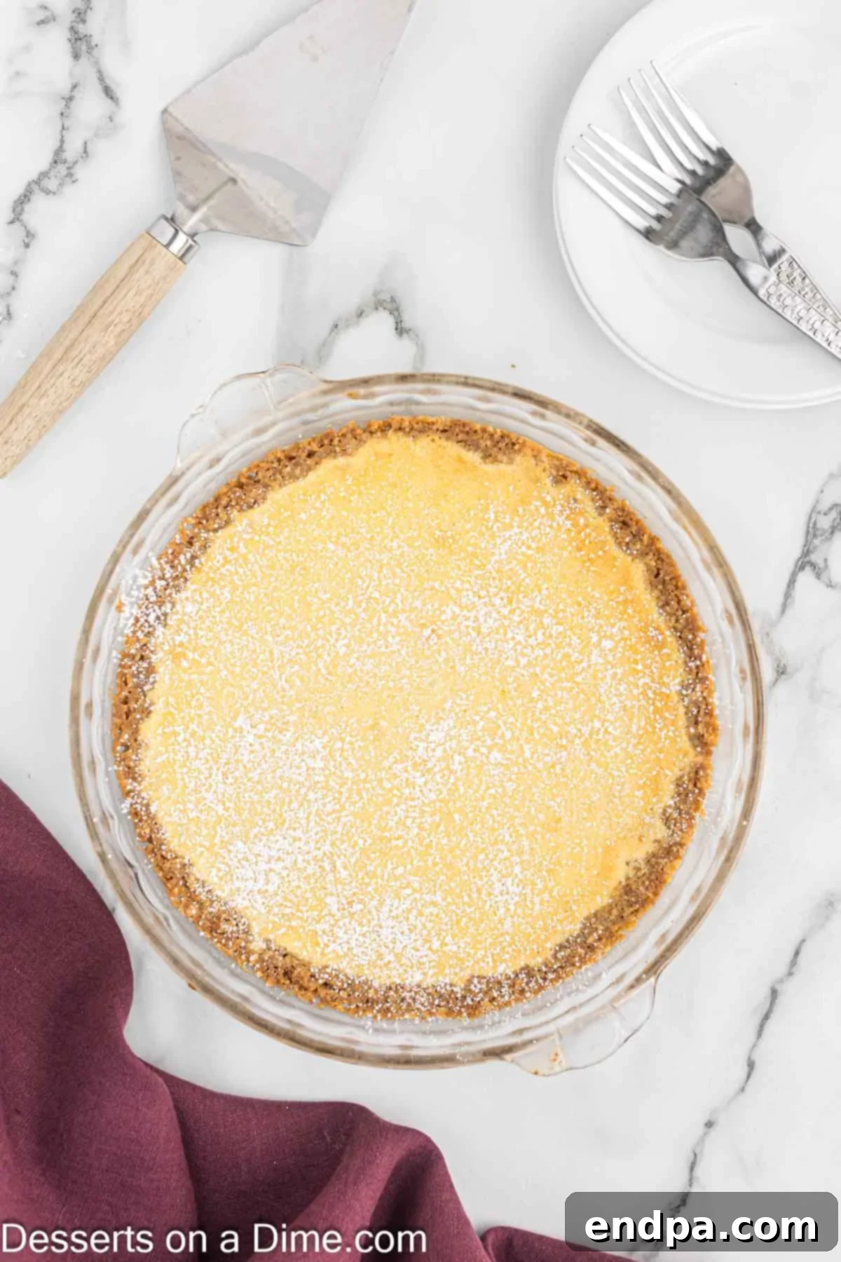 Golden Butter Crunch Pie 18 A whole Crack Pie, beautifully golden brown, dusted generously with powdered sugar on a serving plate.