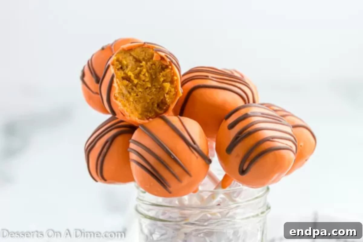 Pumpkin Cake Pops arranged neatly in a glass jar, showcasing their festive orange coating and chocolate drizzle.