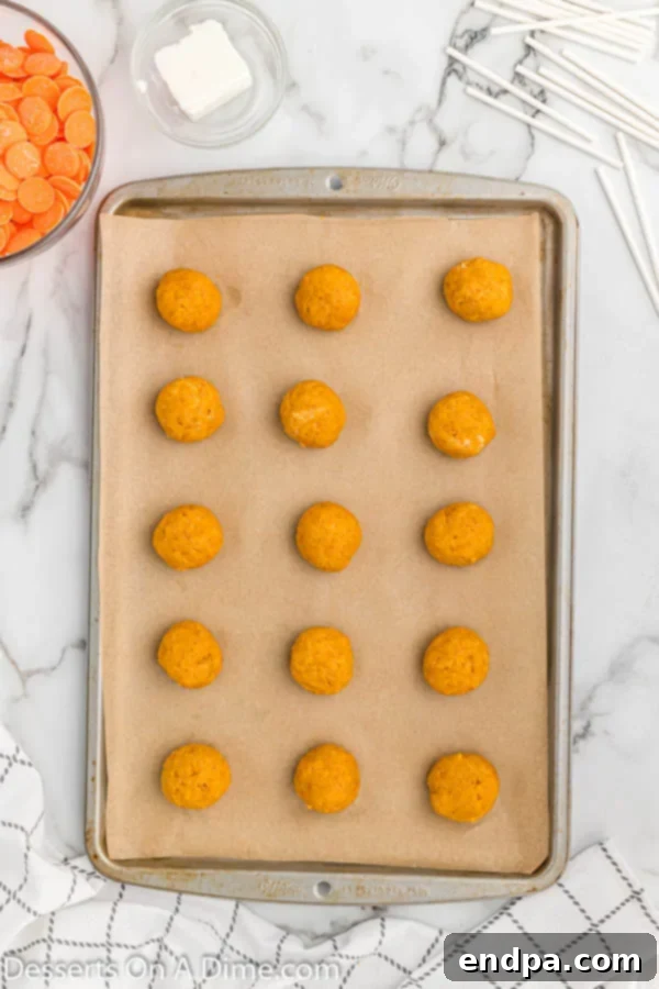 Cake and frosting mixture rolled into uniform balls on a parchment-lined baking sheet.