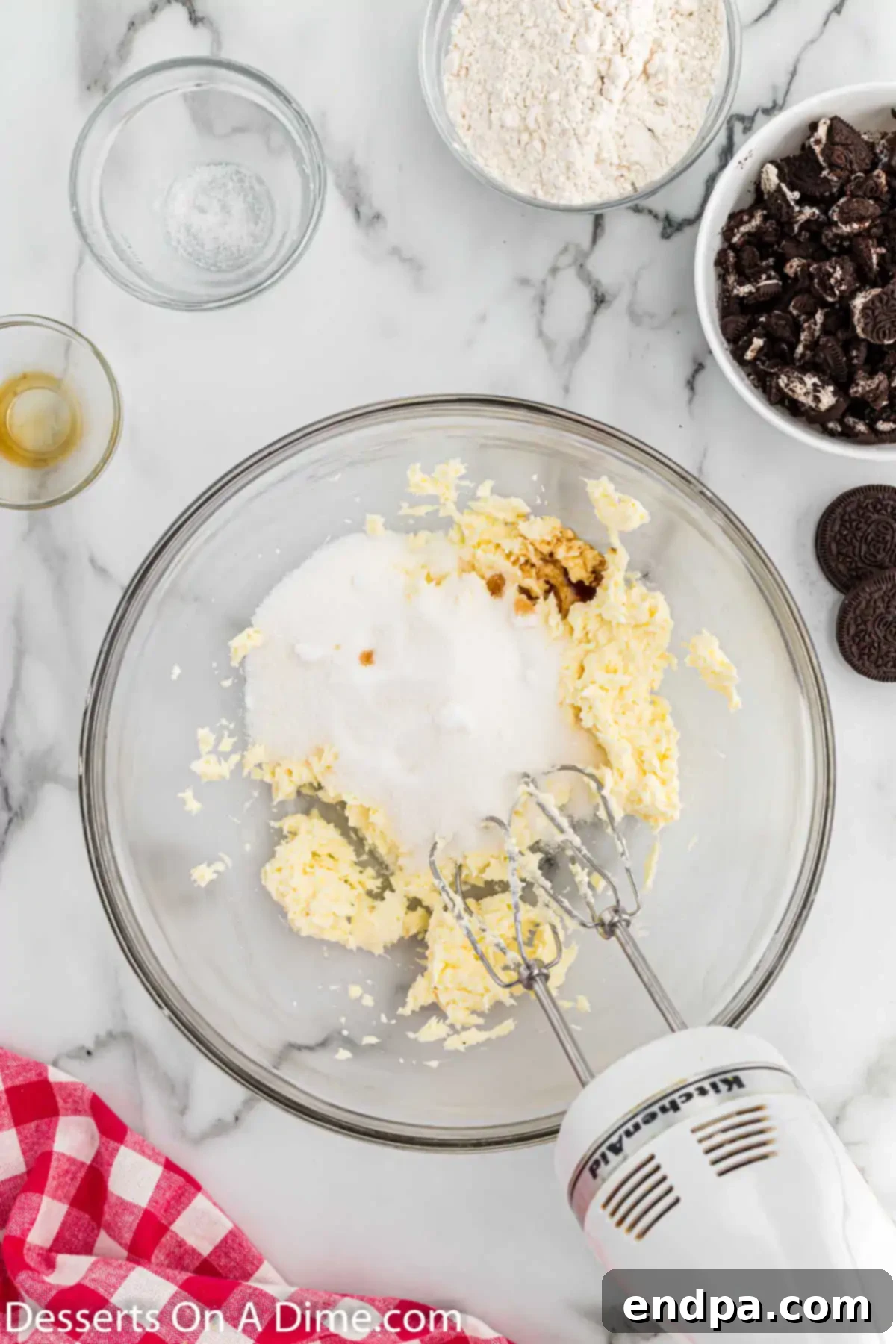 Granulated sugar and vanilla extract being added to the creamed cream cheese and butter mixture in a bowl.