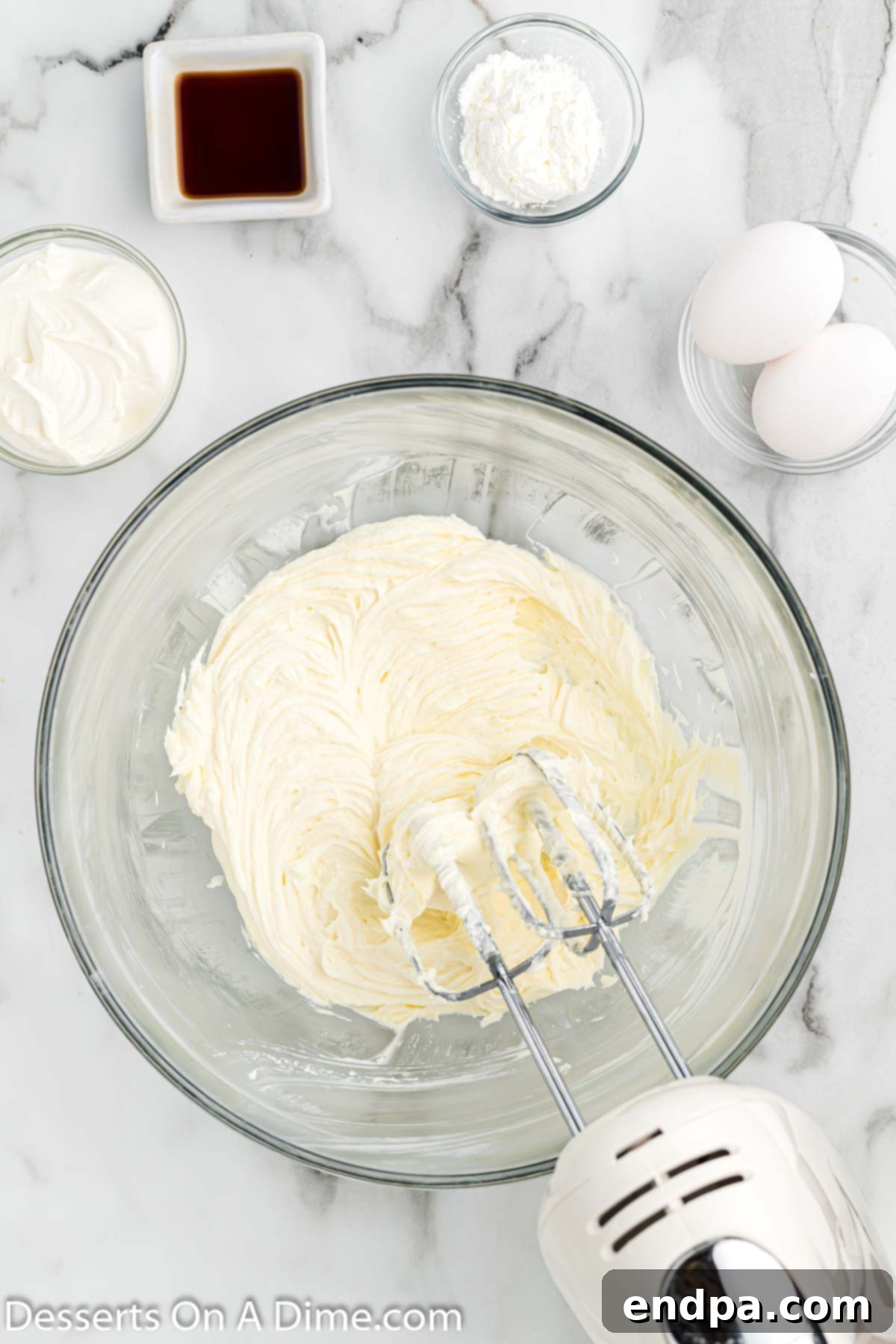 Close-up image of cream cheese being beaten until fluffy in a mixer.