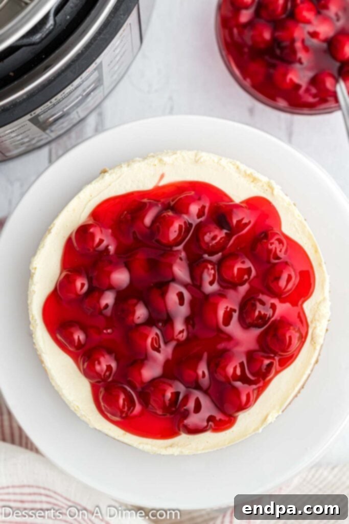 A delicious slice of Instant Pot cheesecake topped with rich cherry pie filling.