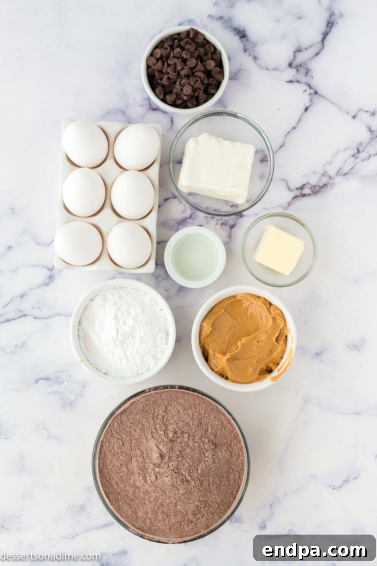 Ultimate Buckeye Brownie Delights 3 Various ingredients for Buckeye Brownie Cookies laid out on a white surface, including a box of brownie mix, sticks of butter, cream cheese, an egg, powdered sugar, creamy peanut butter, and chocolate chips.