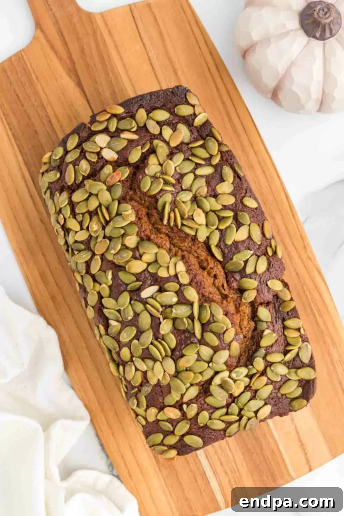 Starbucks Copycat Pumpkin Bread 10 Starbucks pumpkin bread on a cutting board, garnished with pepitas.