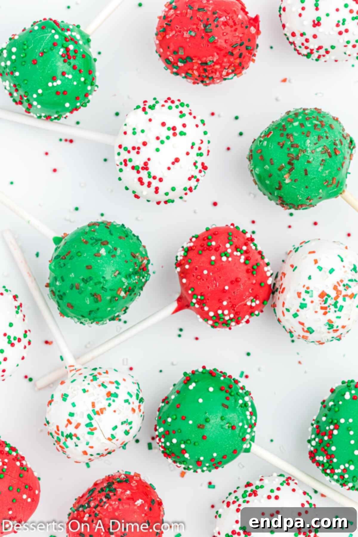 Assortment of red, green, and white Christmas cake pops displayed on a counter.