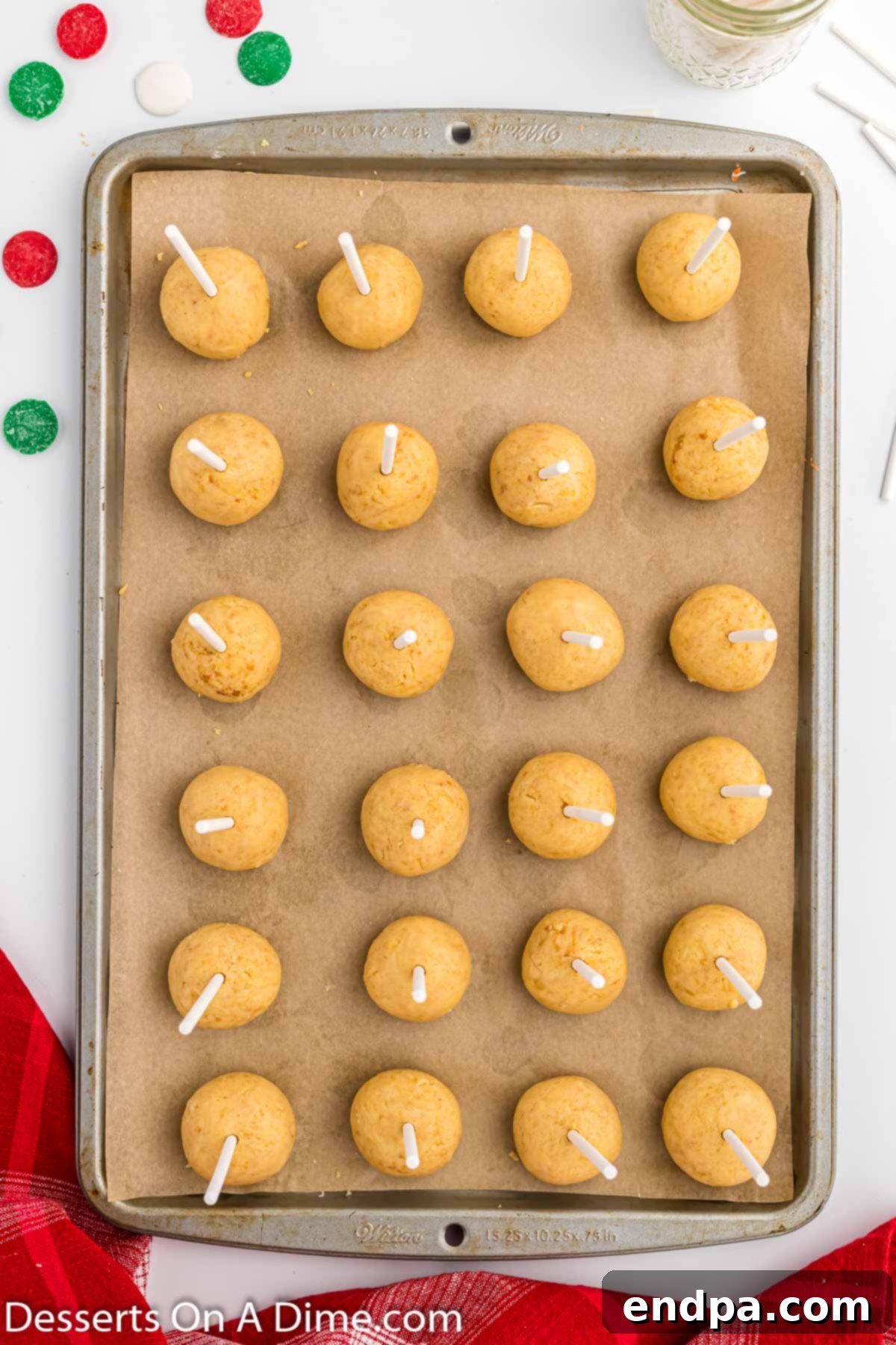 Lollipop sticks inserted into cake balls on a baking sheet.