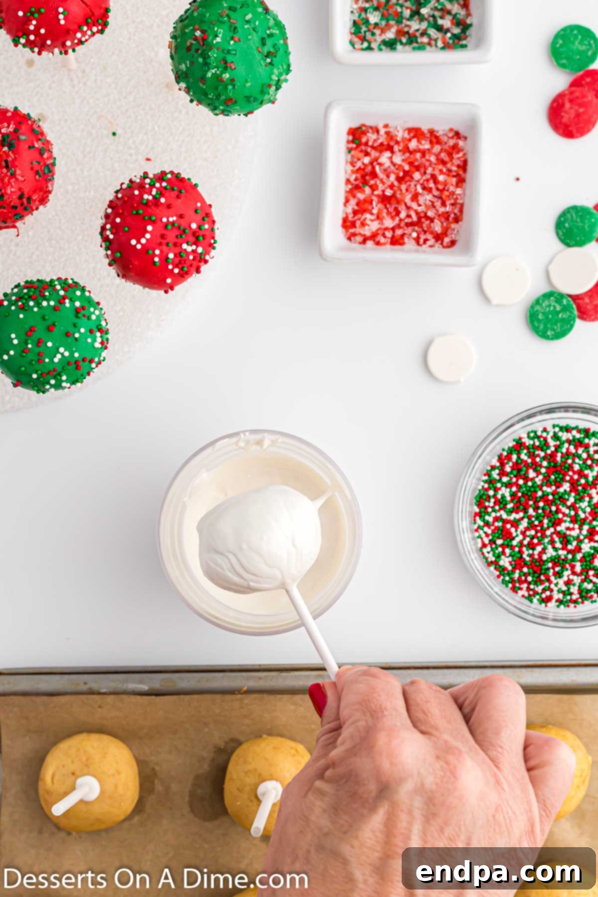 A cake pop being dipped into melted red candy.