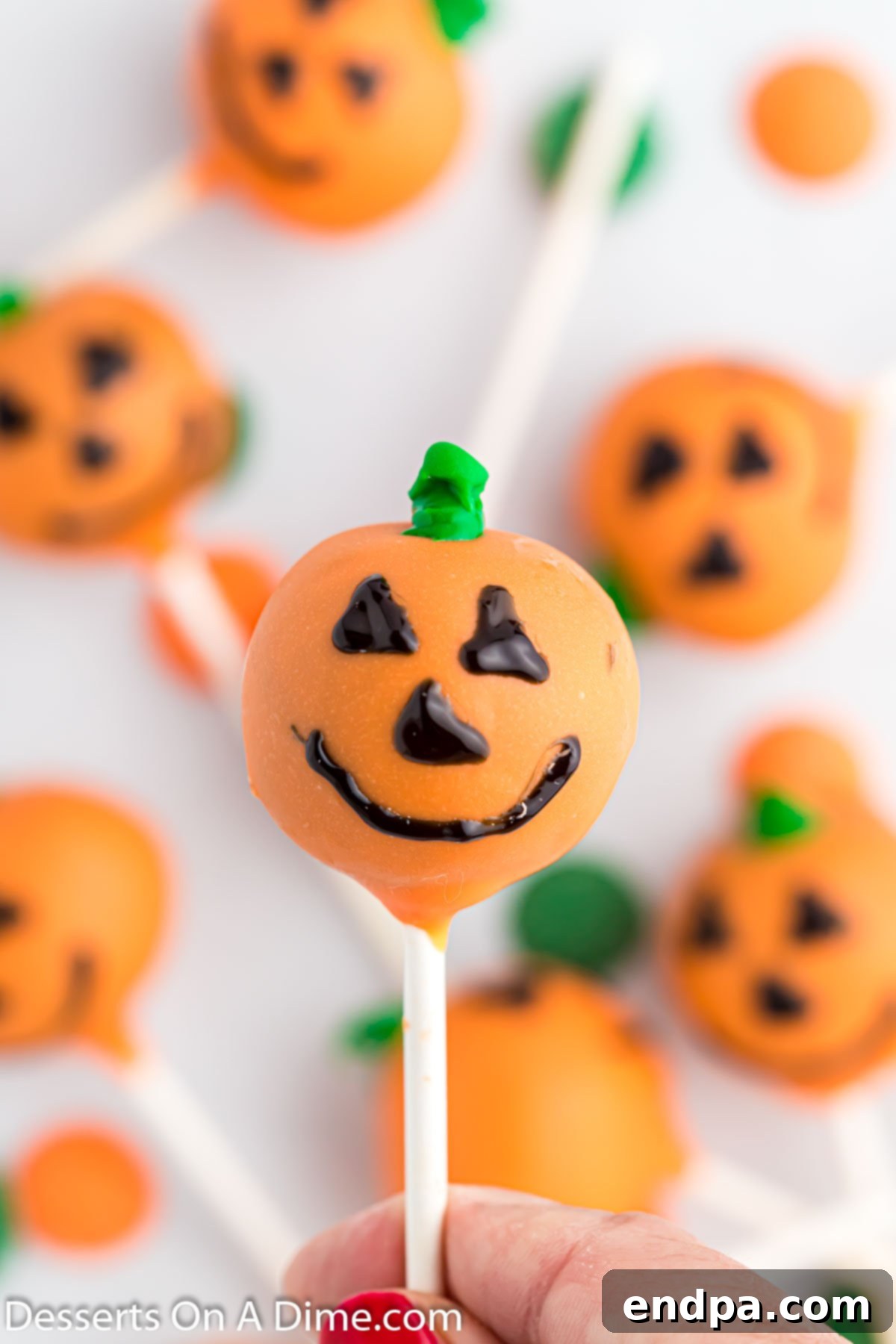 Spooky Sweet Halloween Cake Pops 2 Close-up photo of vibrant orange Halloween cake pops with black Jack-o'-Lantern faces and green stems.