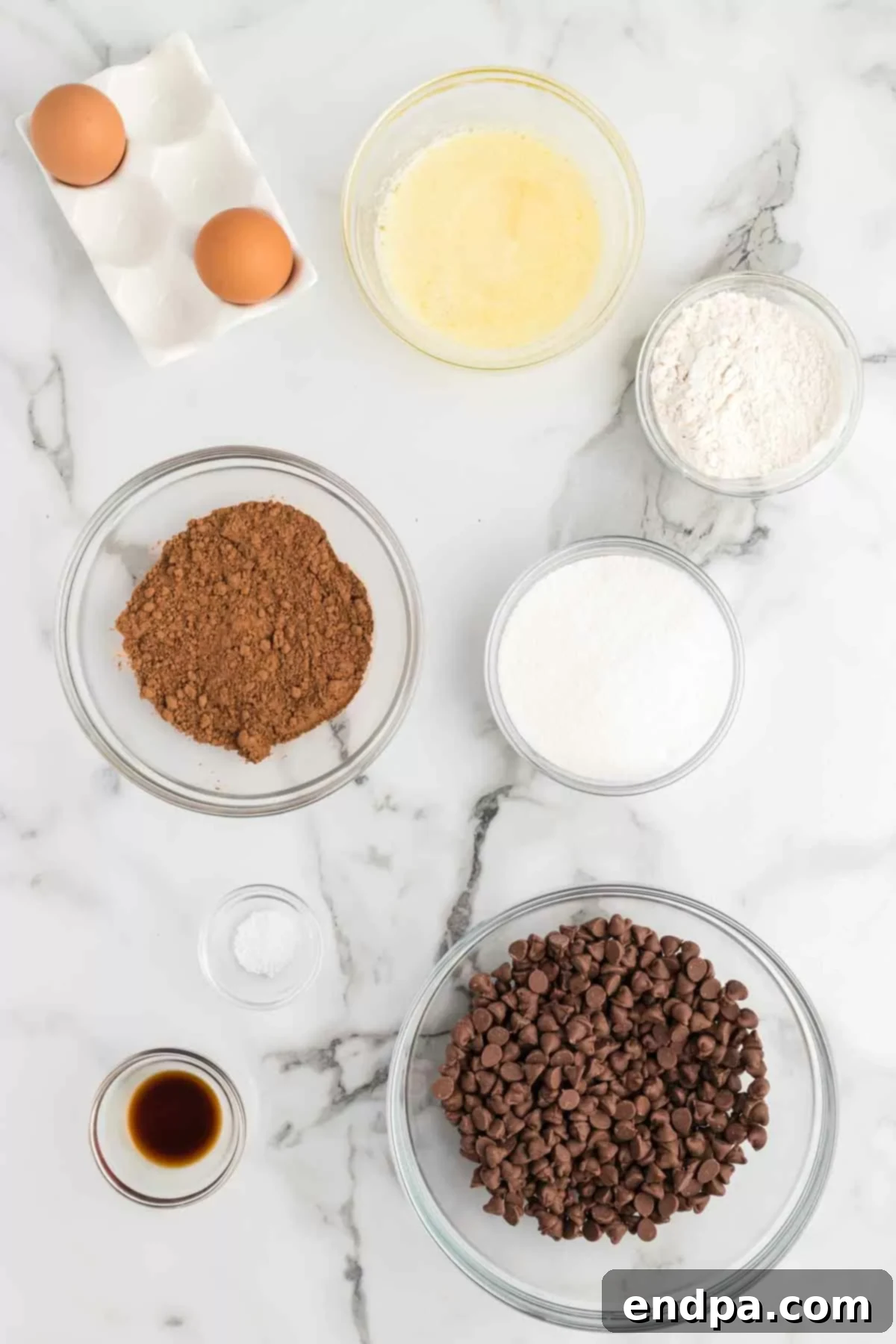 Assortment of baking ingredients laid out for making Starbucks brownies, including butter, sugar, eggs, flour, cocoa powder, and chocolate chips.