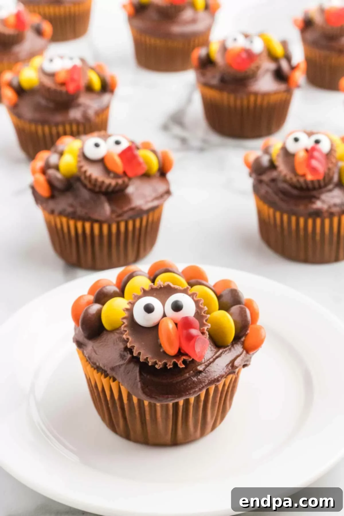 Close-up of a decorated Turkey Cupcake, showcasing its vibrant candy feathers, mini Reese's face, and playful candy eyes, ready to delight.
