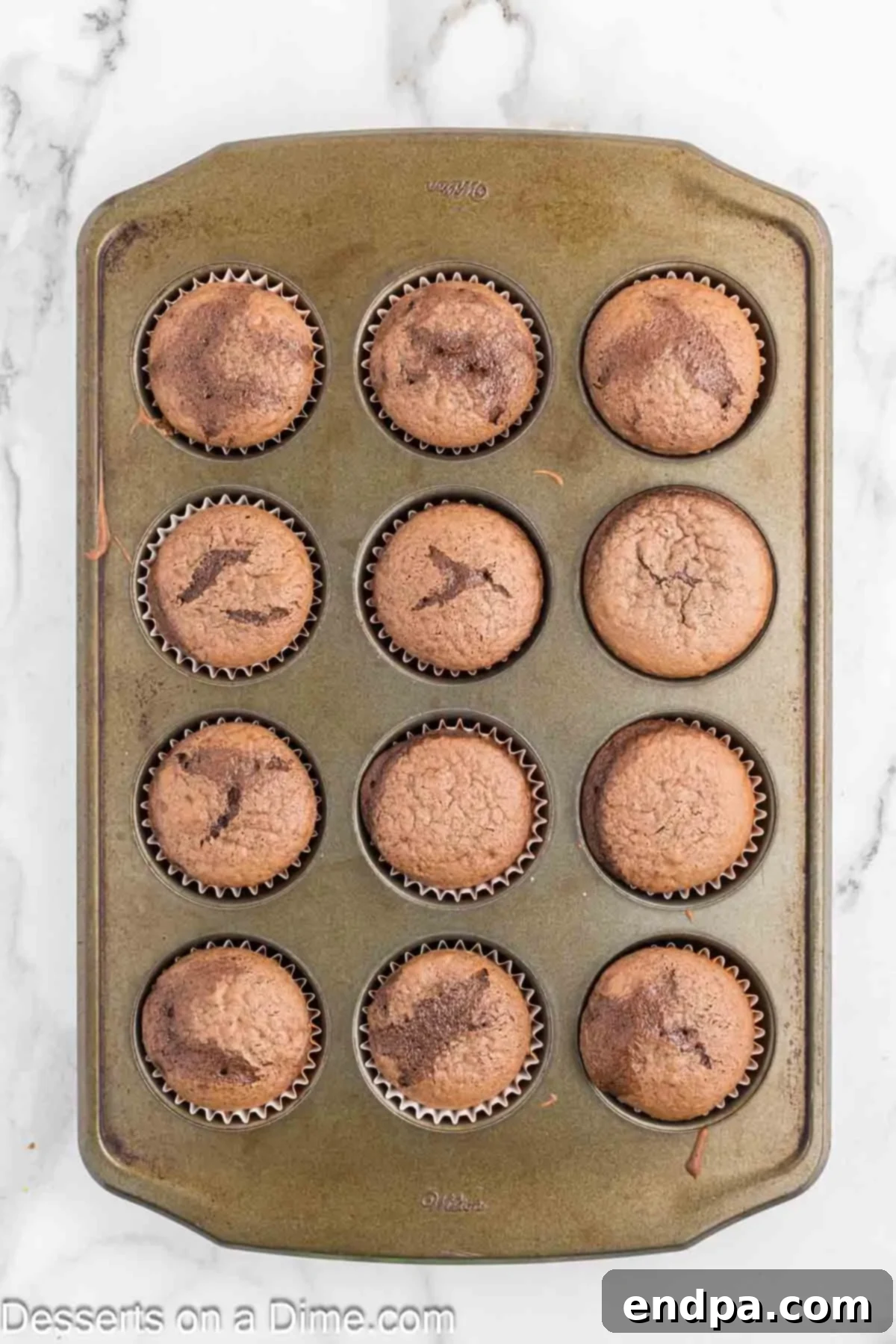 Freshly baked cupcakes cooling in their orange liners on a wire rack.