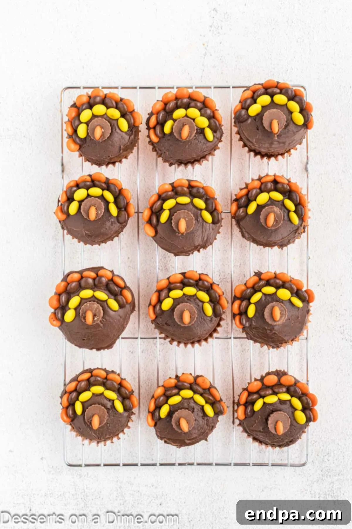 A cupcake showing a mini Reese's cup face with an orange Reese's Piece cut in half and placed as the turkey's nose.