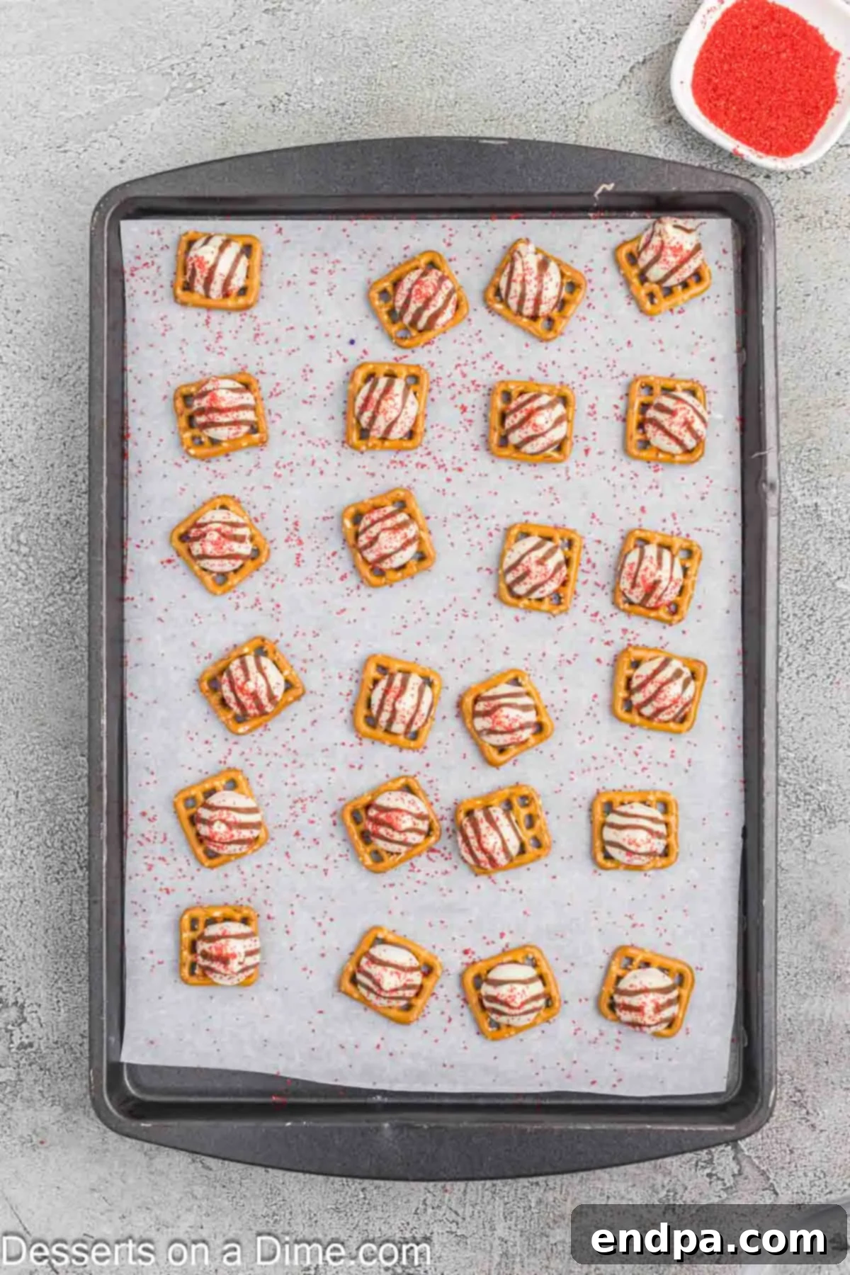 Red sanding sugar sprinkled over the melted chocolate on pretzels.