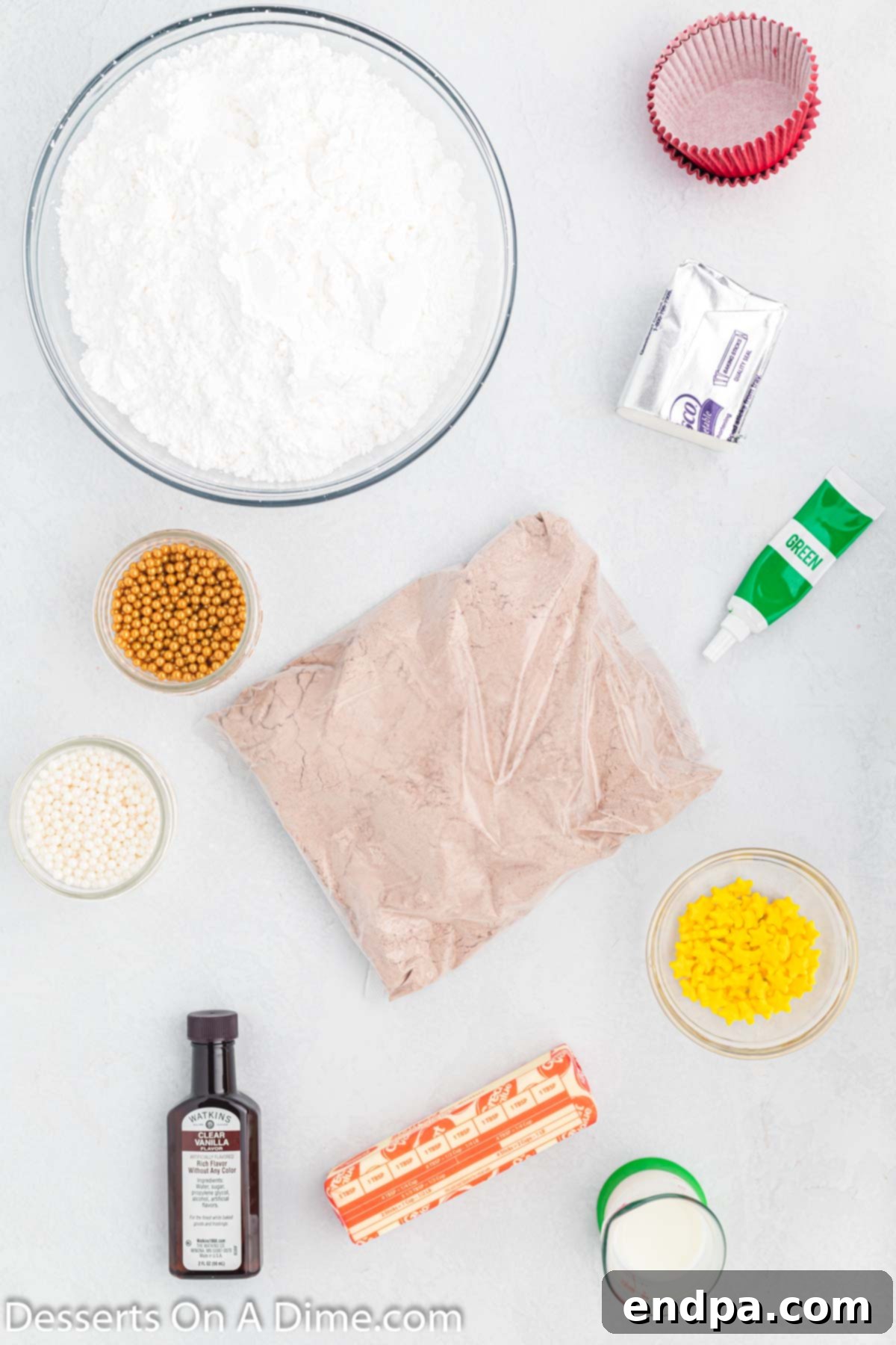 Ingredients for Christmas tree cupcakes including cake mix, shortening, butter, vanilla extract, powdered sugar, milk, green gel food coloring, yellow sugar stars, and candy balls.