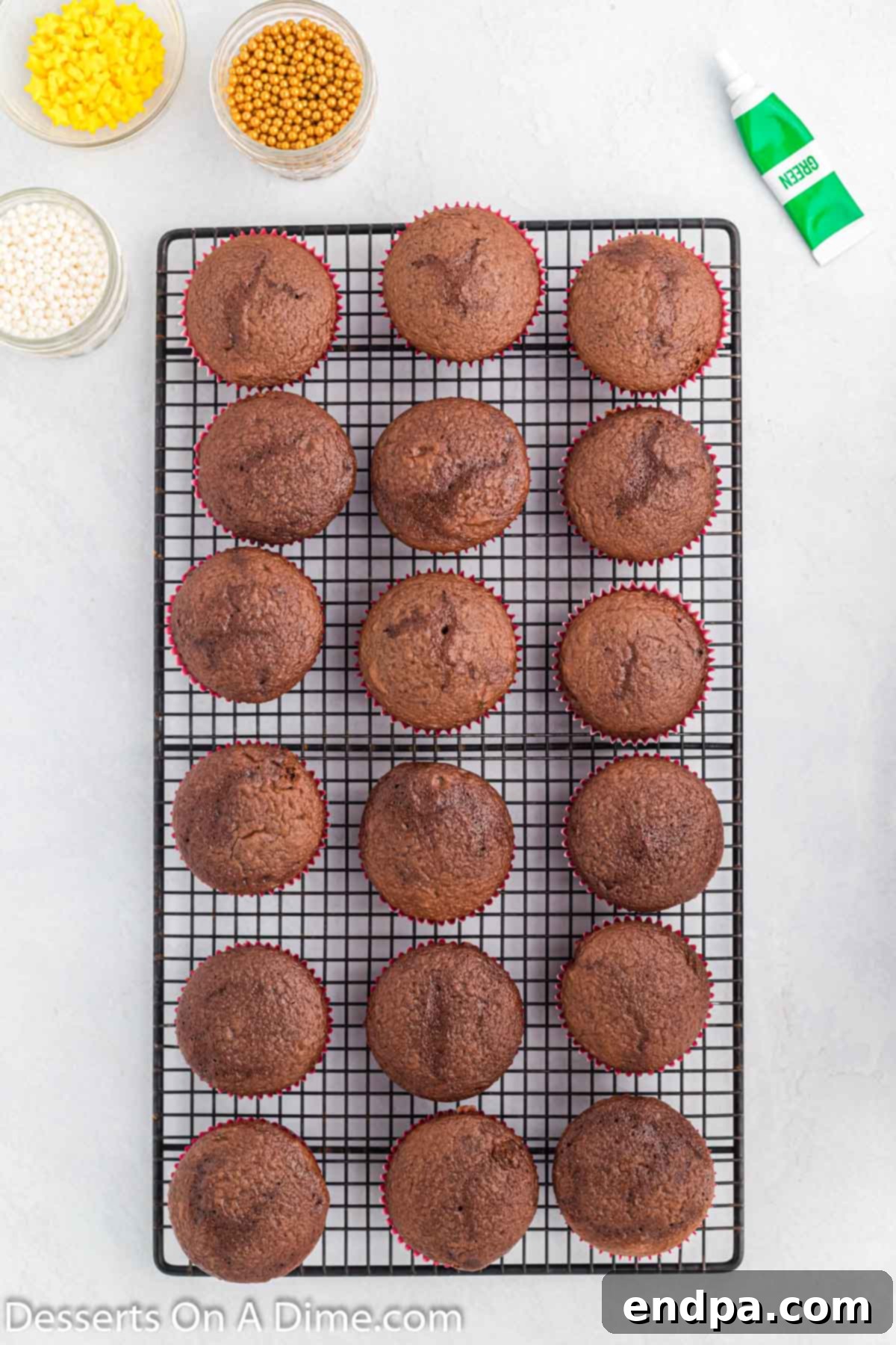 Freshly baked cupcakes cooling on a wire rack after being removed from the oven.