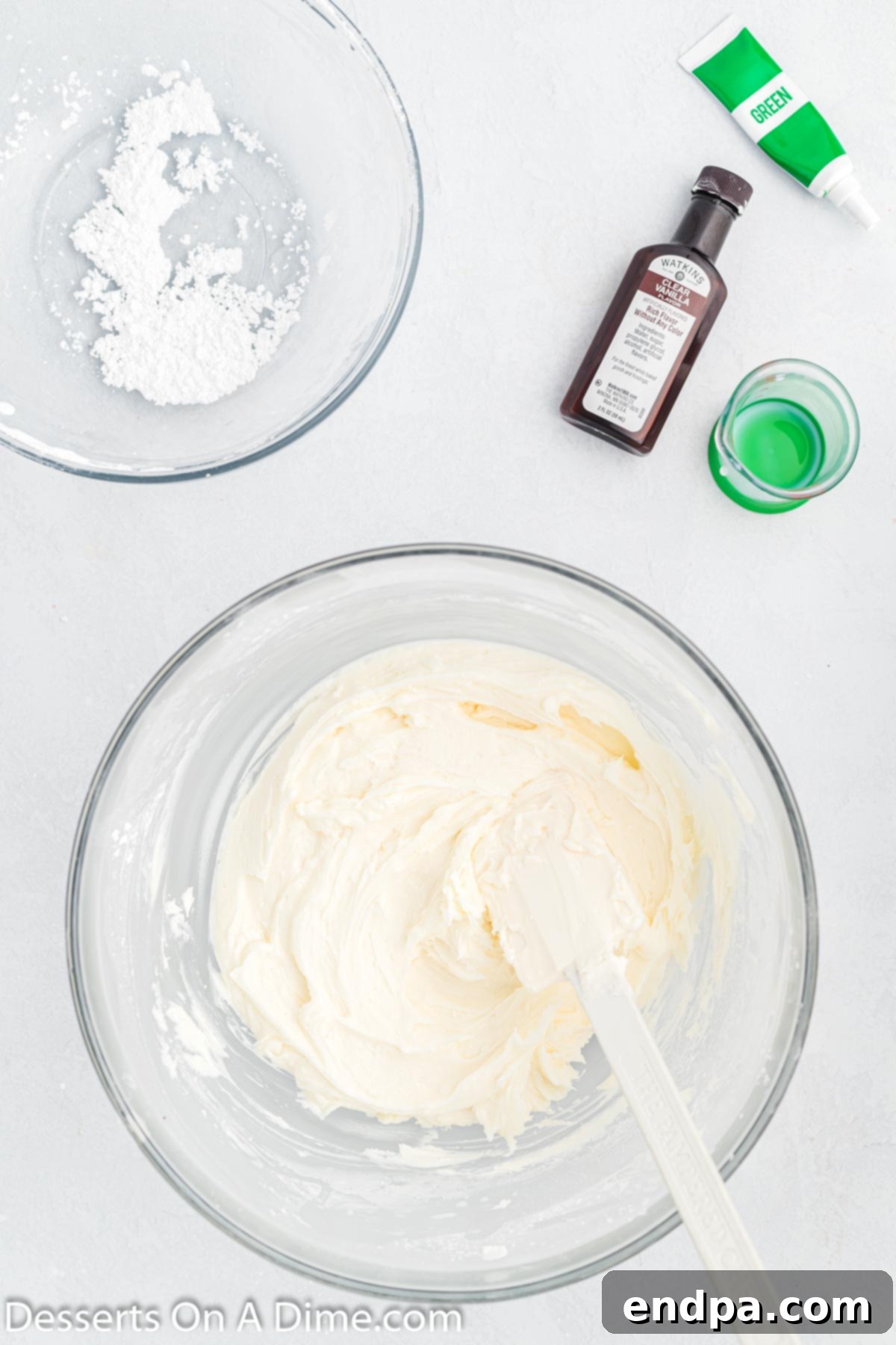 Milk and clear vanilla extract being added to the frosting mixture in a bowl, then whisked until smooth.