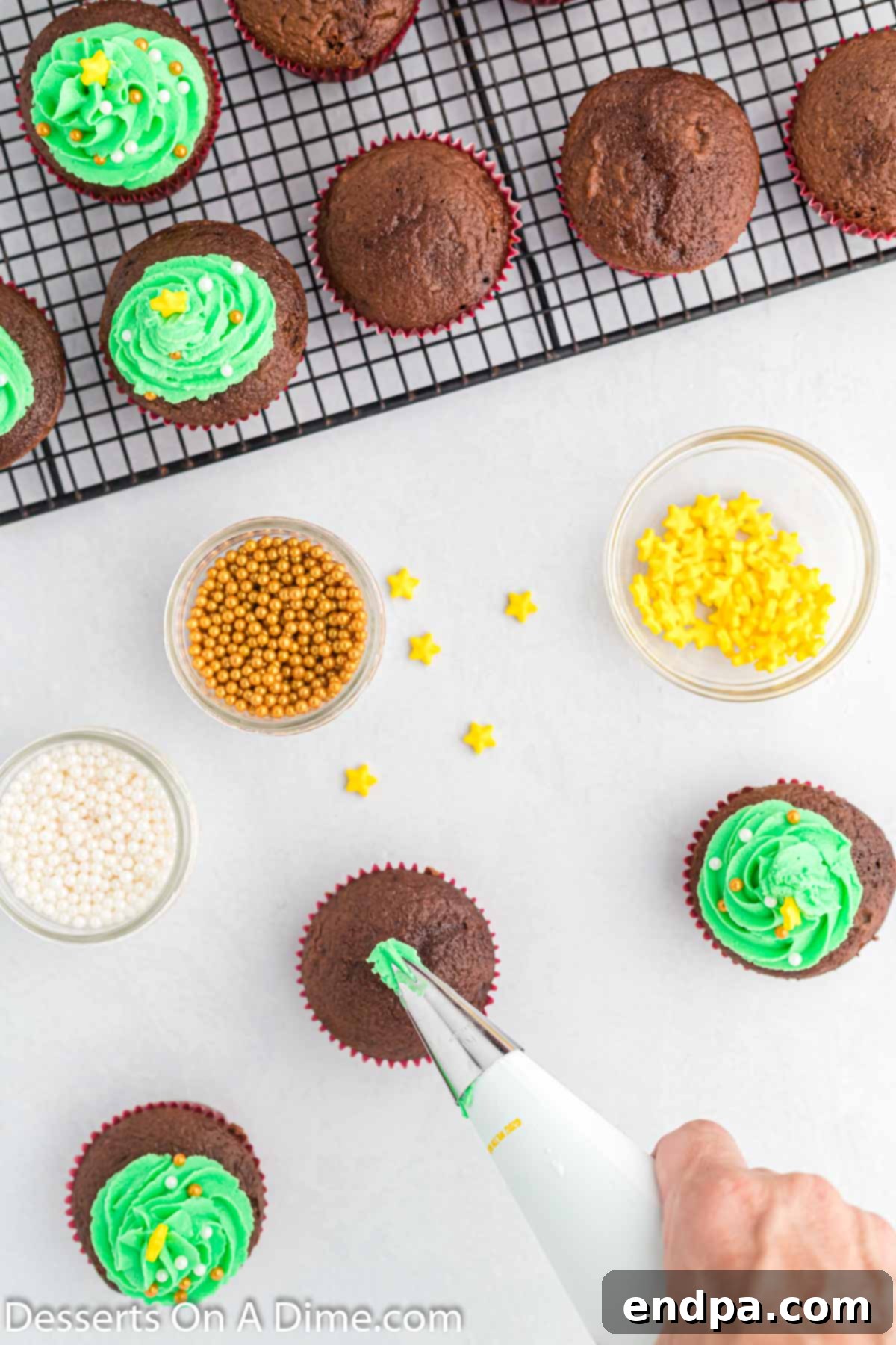 Green frosting being swirled onto a cupcake in a circular motion, gradually building up to resemble a Christmas tree shape.