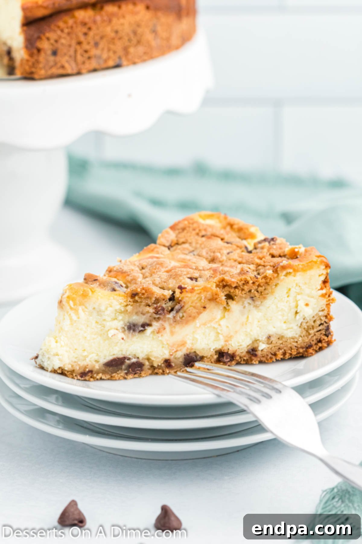 Cookie Dough Dream Cheesecake 2 A perfectly sliced piece of Chocolate Chip Cookie Cheesecake on a white plate, showcasing its distinct cookie crust and creamy cheesecake layers, ready to be enjoyed.