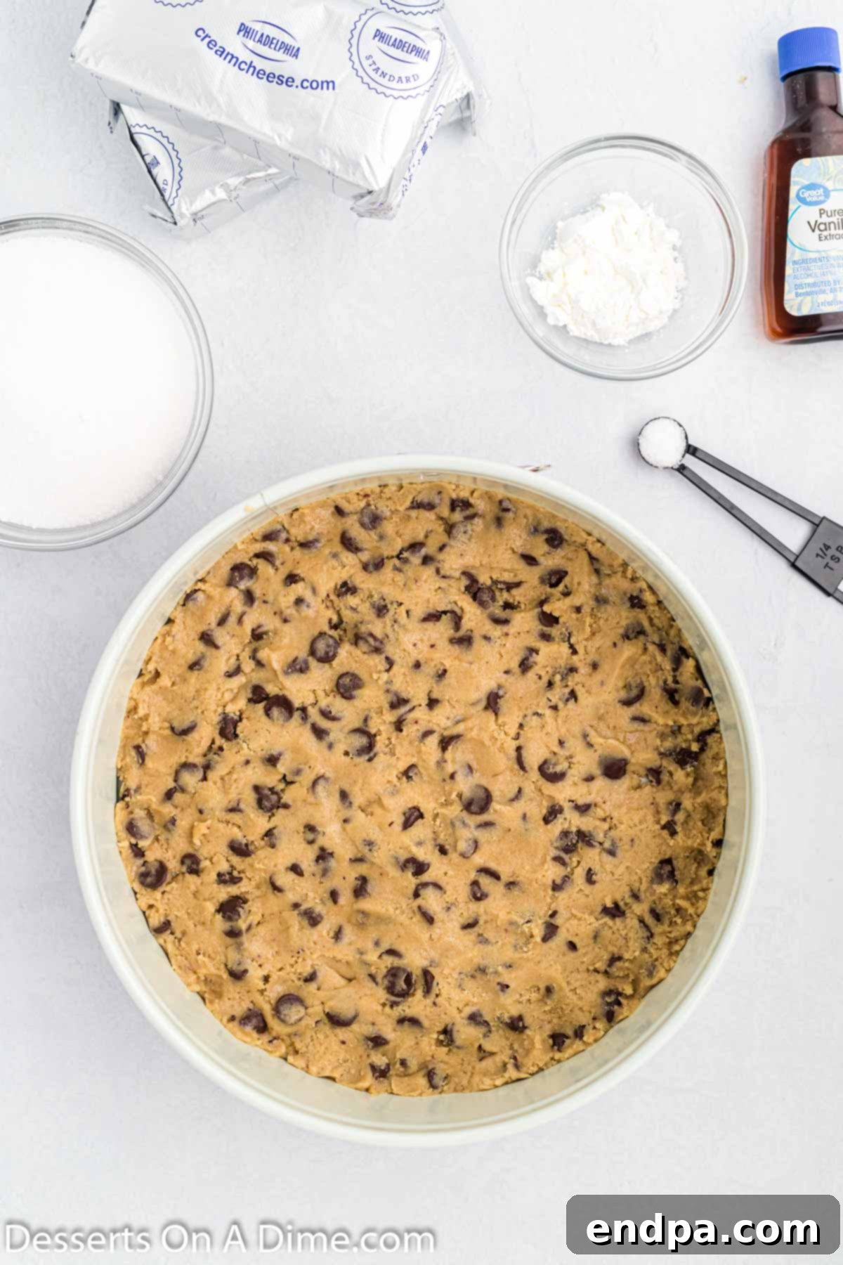 Cookie Dough Dream Cheesecake 4 Chocolate chip cookie dough expertly pressed into the bottom of a 9-inch springform pan, creating a sturdy and delicious base for the cheesecake.