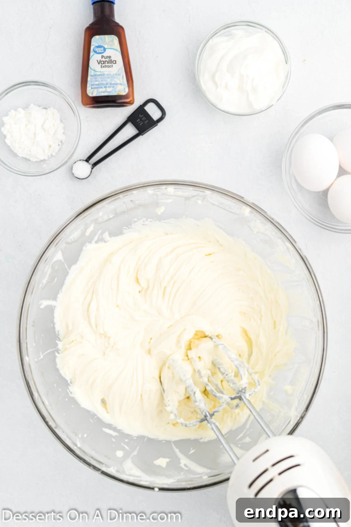 Cookie Dough Dream Cheesecake 5 Softened cream cheese and granulated sugar being creamed together in a large mixing bowl, showcasing a smooth, lump-free consistency achieved with a hand mixer.