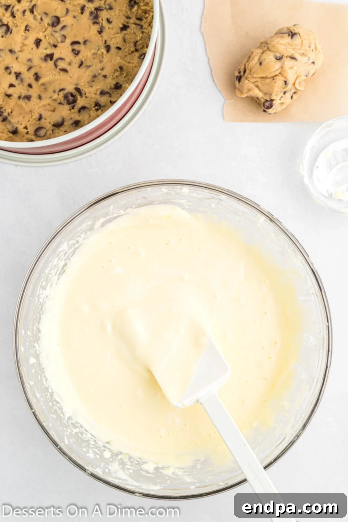 Cookie Dough Dream Cheesecake 6 Sour cream being gently folded into the smooth and creamy cheesecake batter in a mixing bowl, illustrating the careful technique to combine ingredients without overmixing.