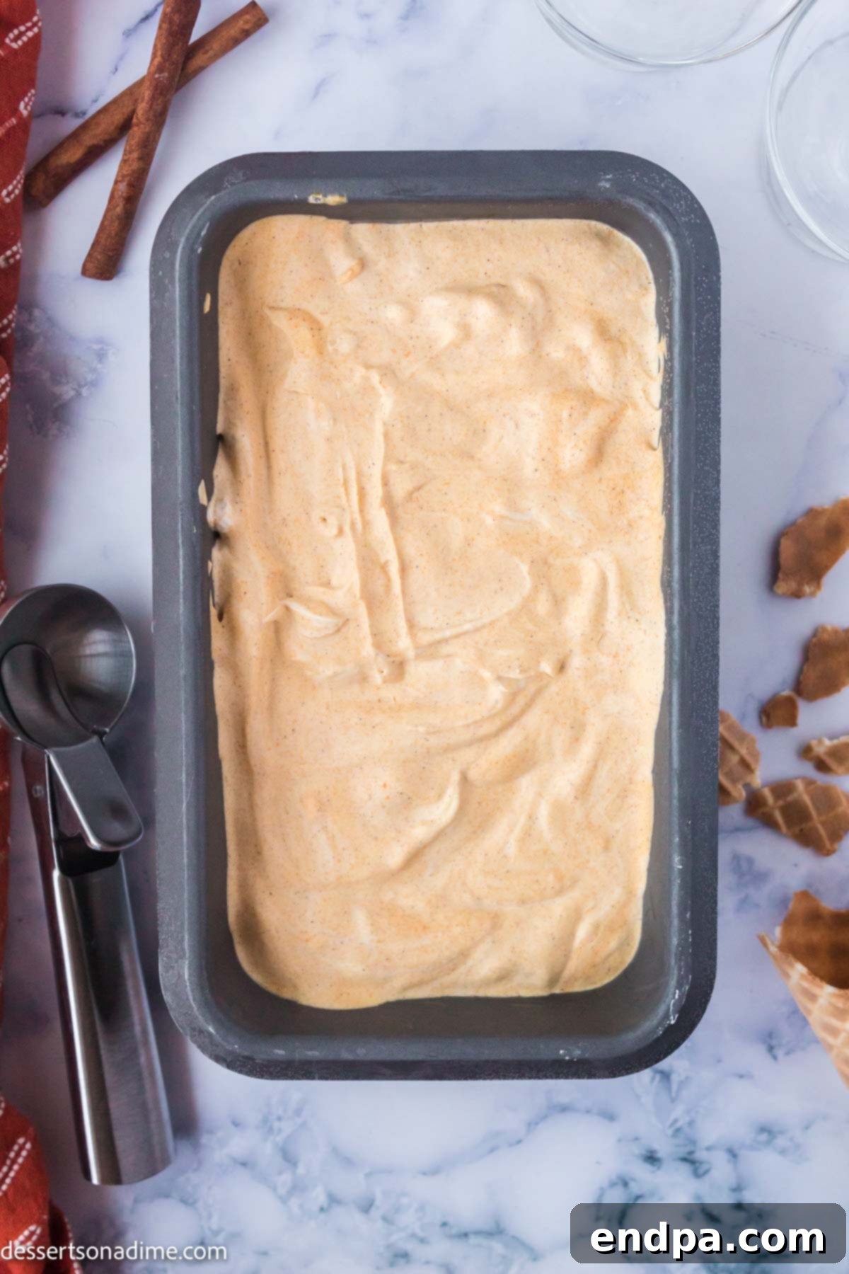 The pumpkin ice cream mixture frozen solid in a loaf pan, indicating it's ready to be scooped and served.