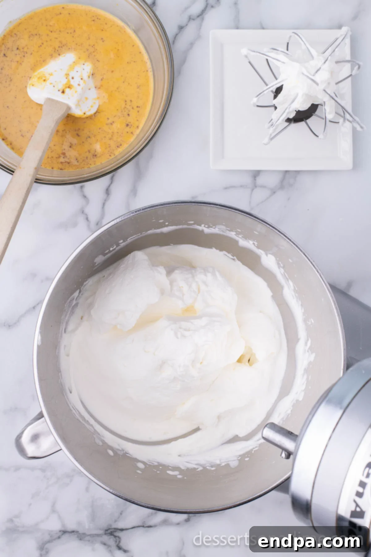 Electric mixer beating heavy cream and vanilla until soft peaks form, showing the cream's whipped texture.