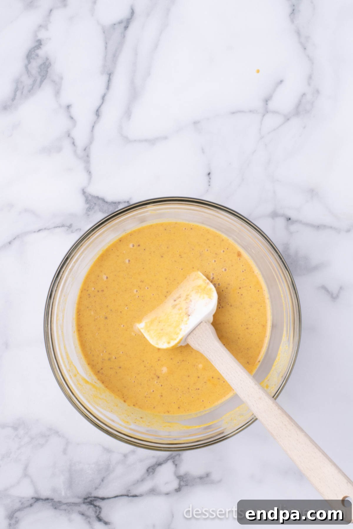 All the pumpkin mixture ingredients—pumpkin puree, sweetened condensed milk, and pumpkin pie spice—thoroughly combined in a mixing bowl.