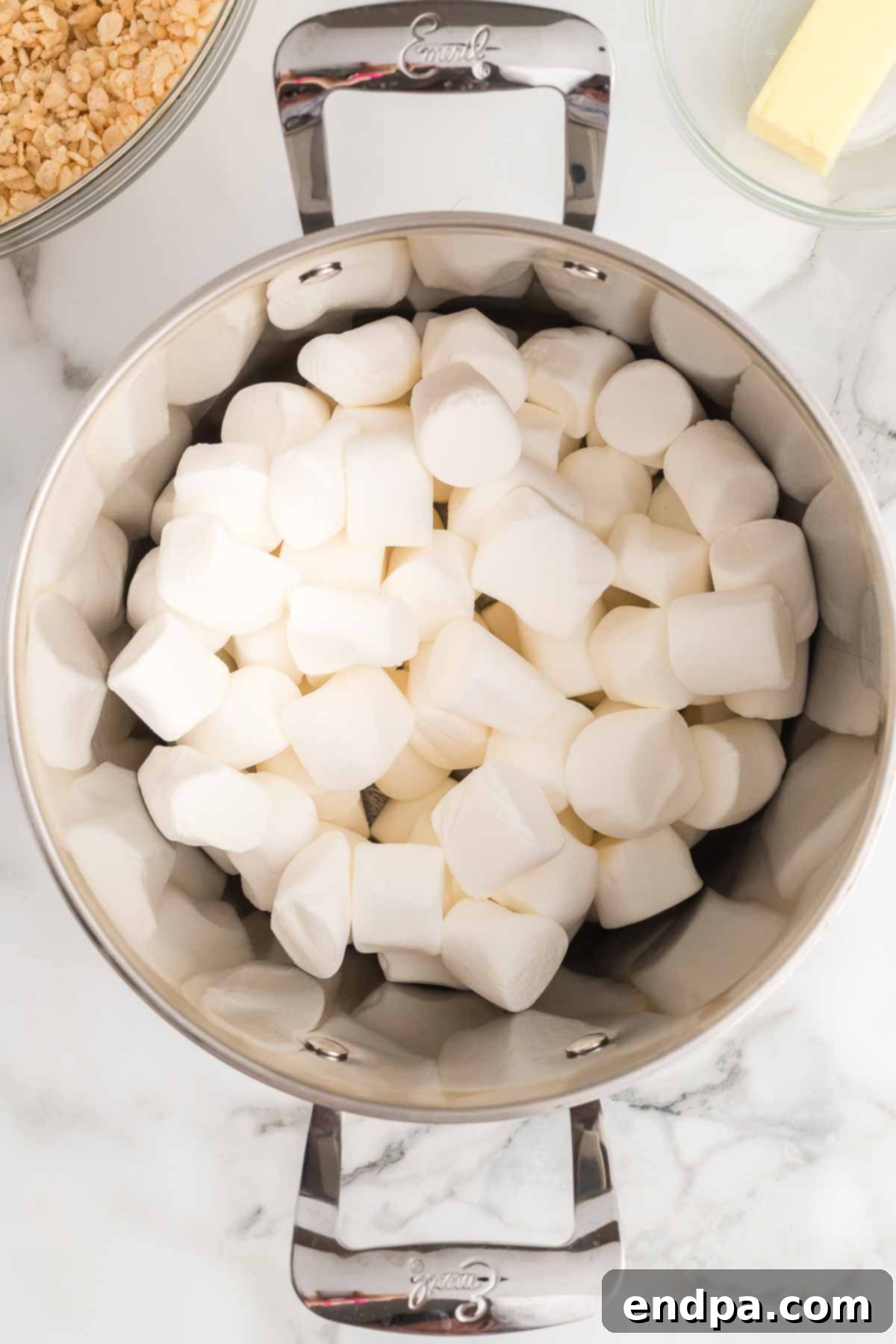 Jolly Krispie Delights 4 A saucepan on a stovetop with butter and marshmallows melting together, creating a gooey mixture.