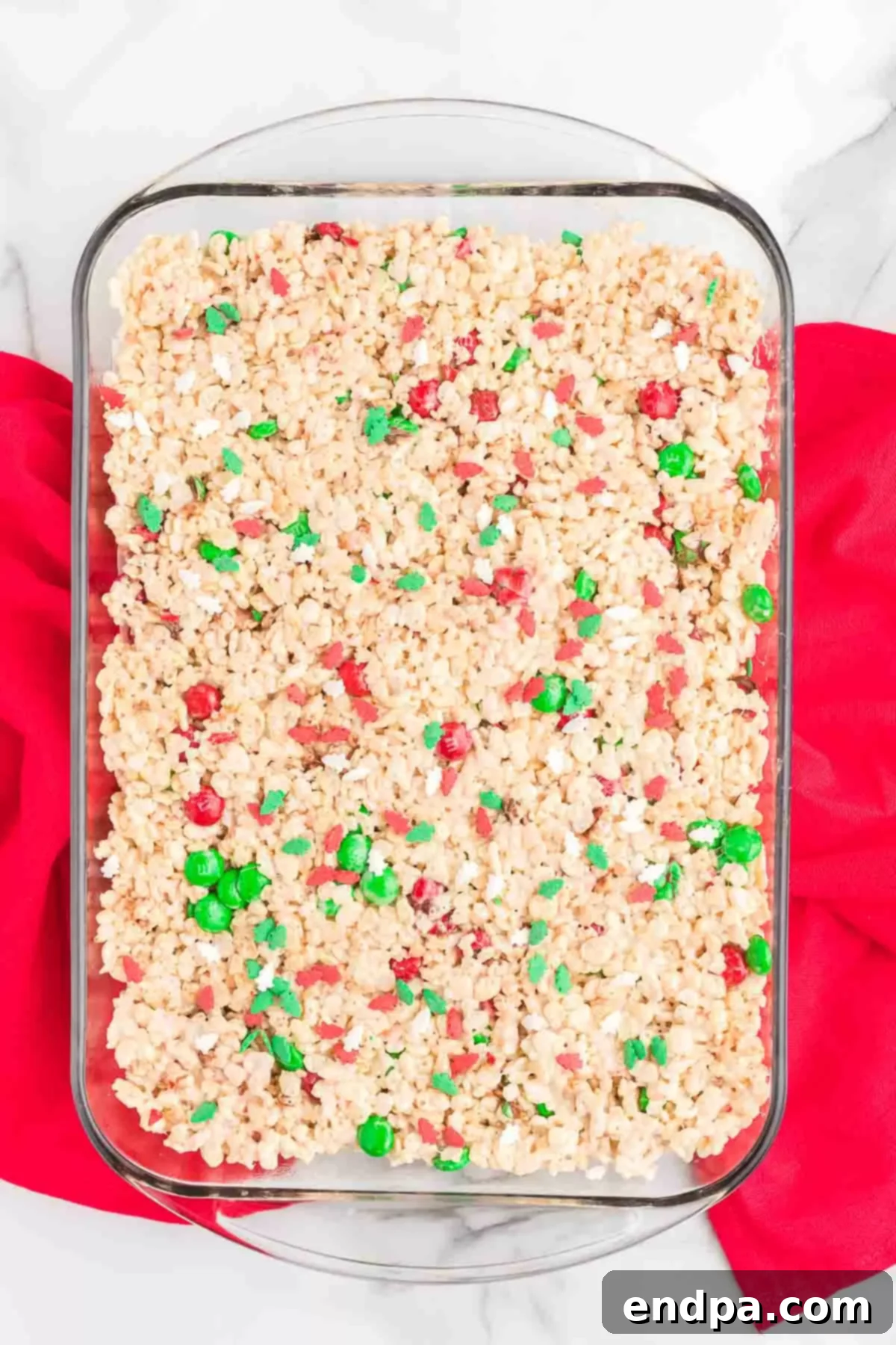 Jolly Krispie Delights 9 The Christmas Rice Krispie Treat mixture pressed evenly into a baking dish, adorned with sprinkles and M&M's.