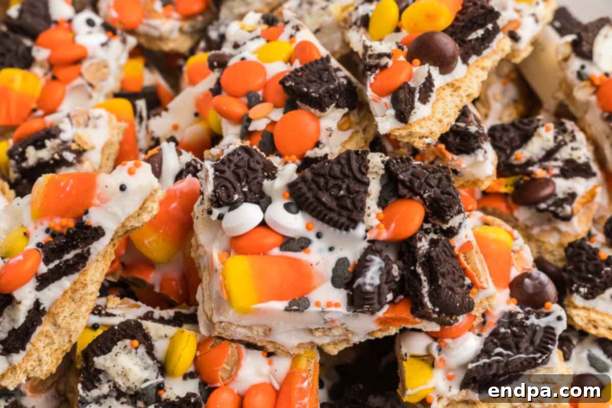 Halloween Bark broken into pieces and piled together, showcasing its vibrant candies and chocolate swirls.