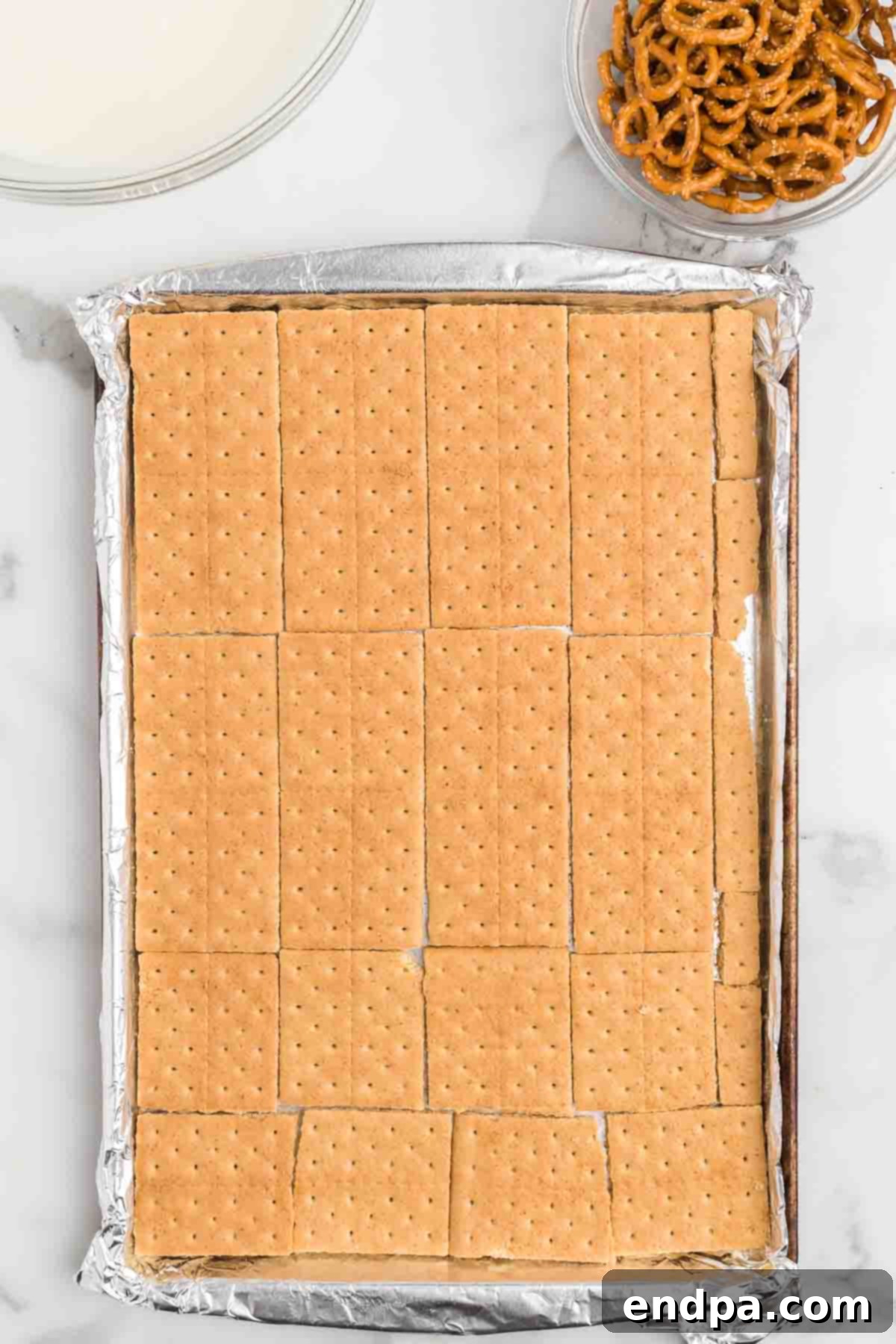 Lining a jelly roll pan with graham crackers as the base for Halloween bark.