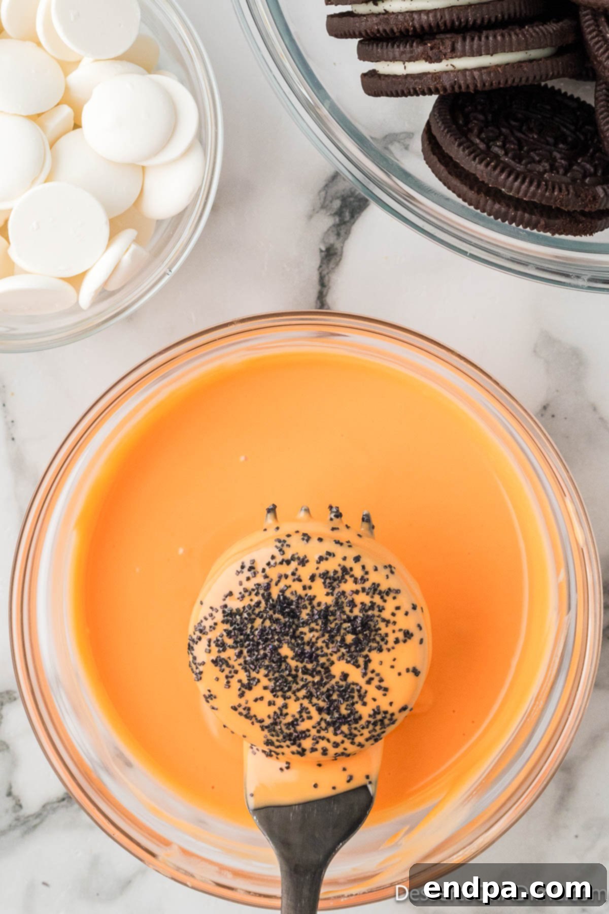 An orange coated Oreo cookie adorned with an assortment of Halloween sprinkles.