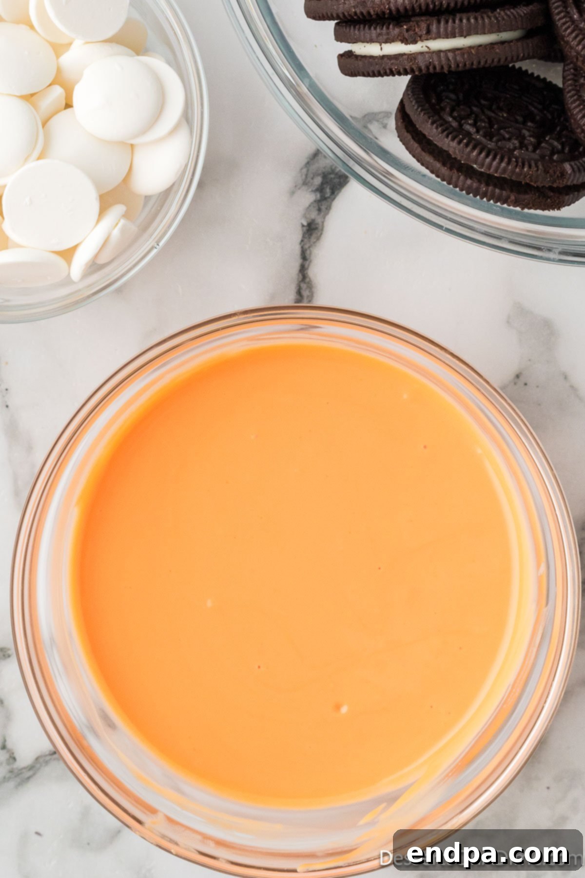 A bowl of fully melted and smooth orange candy melts.