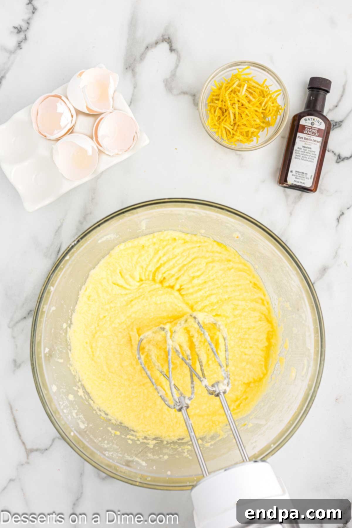 Eggs being added one by one to the creamed butter and sugar mixture.
