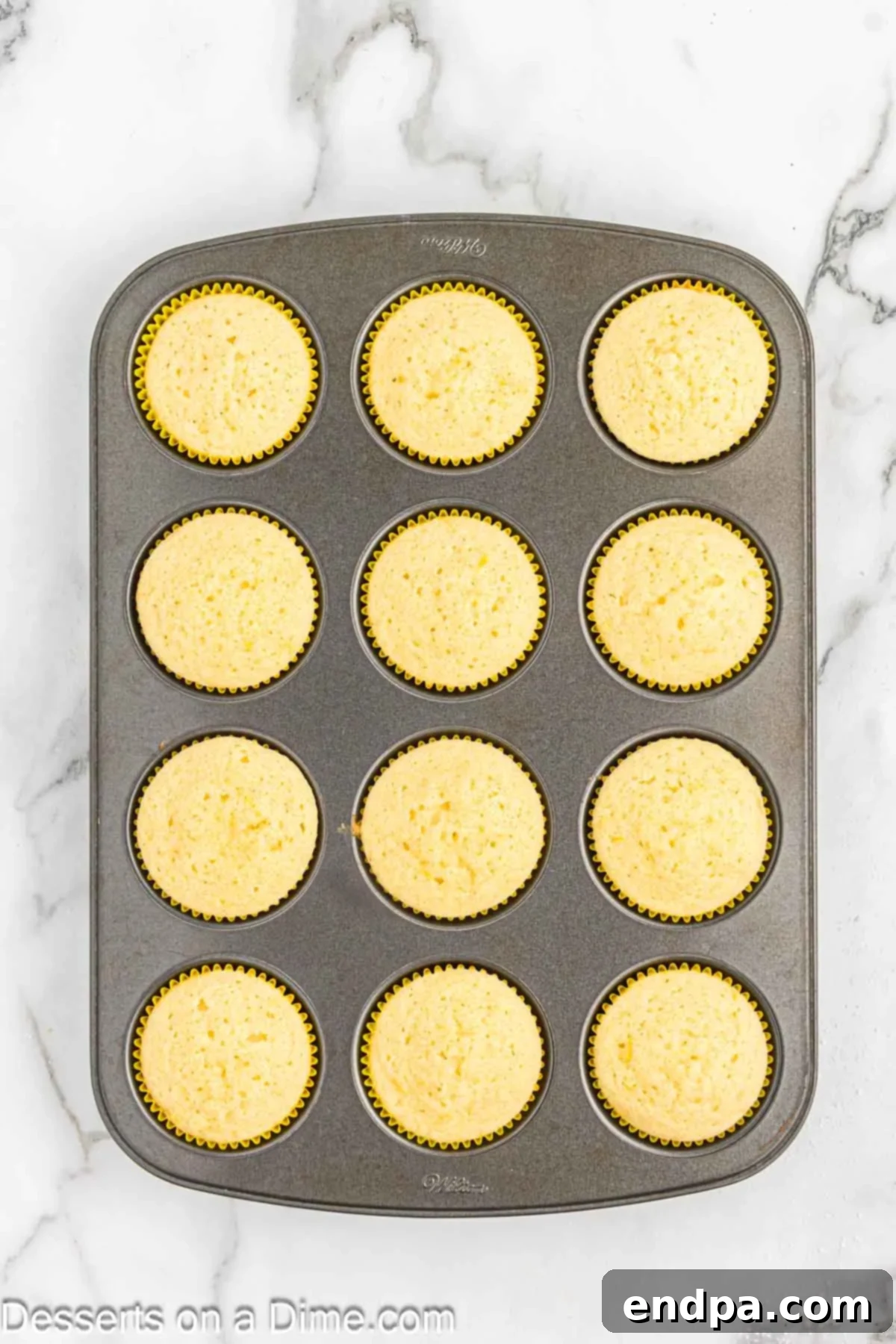 Baked cupcakes cooling in the muffin pan on a wire rack.