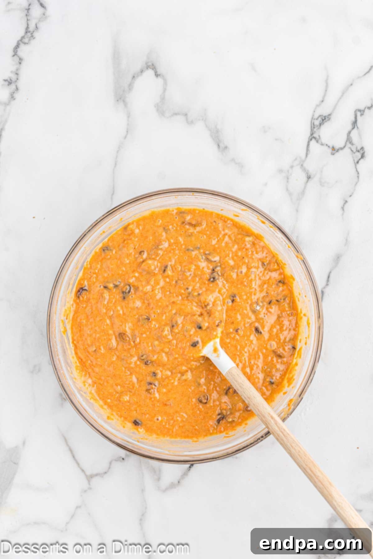 Irresistible Carrot Cake Cupcakes 7 Carrot mixture being added to the dry ingredients in a bowl.